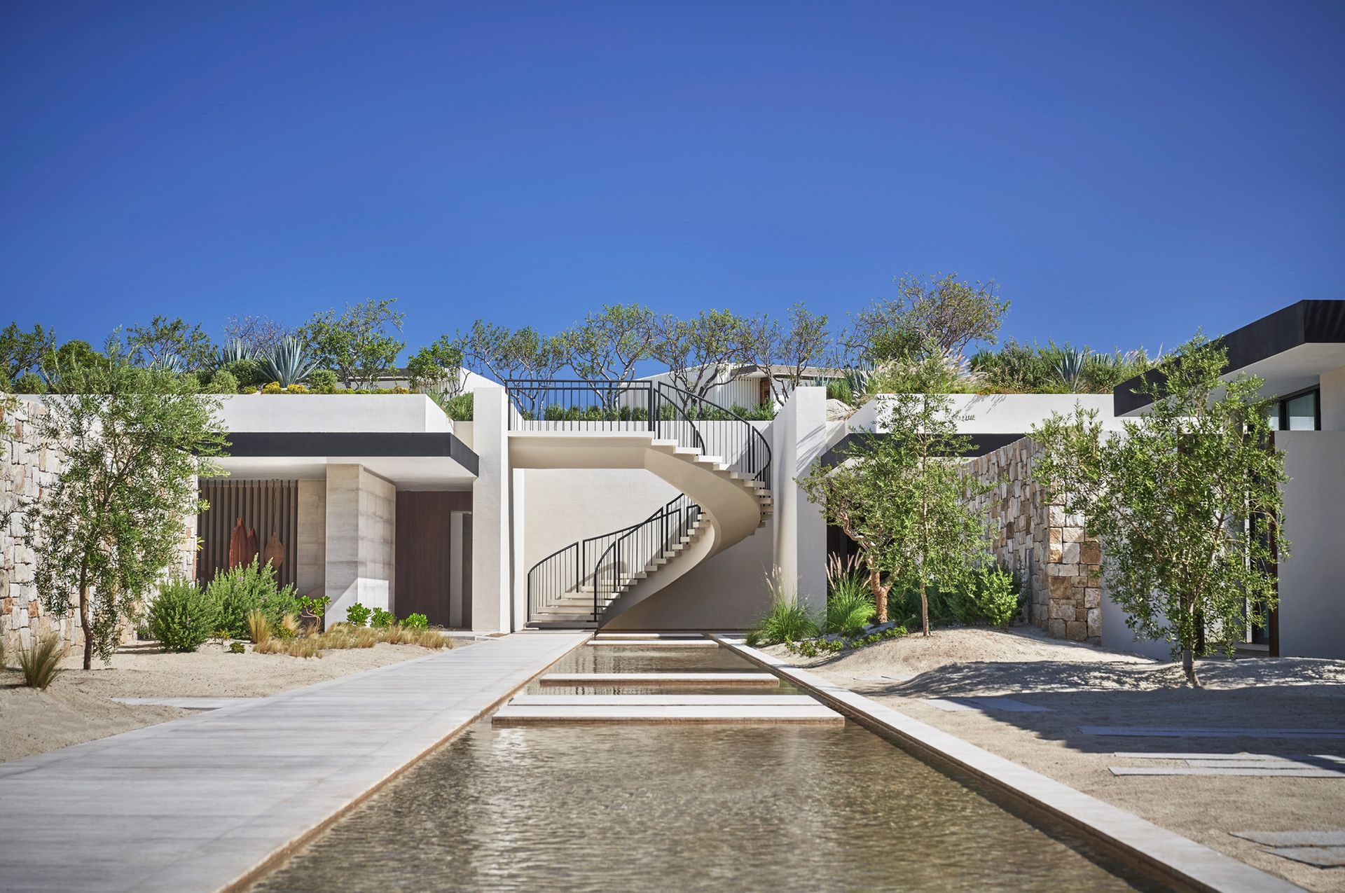 A modern house with a spiral staircase and a pond in front of it in Los Cabos, Mexico at Four Seasons Hotel. 