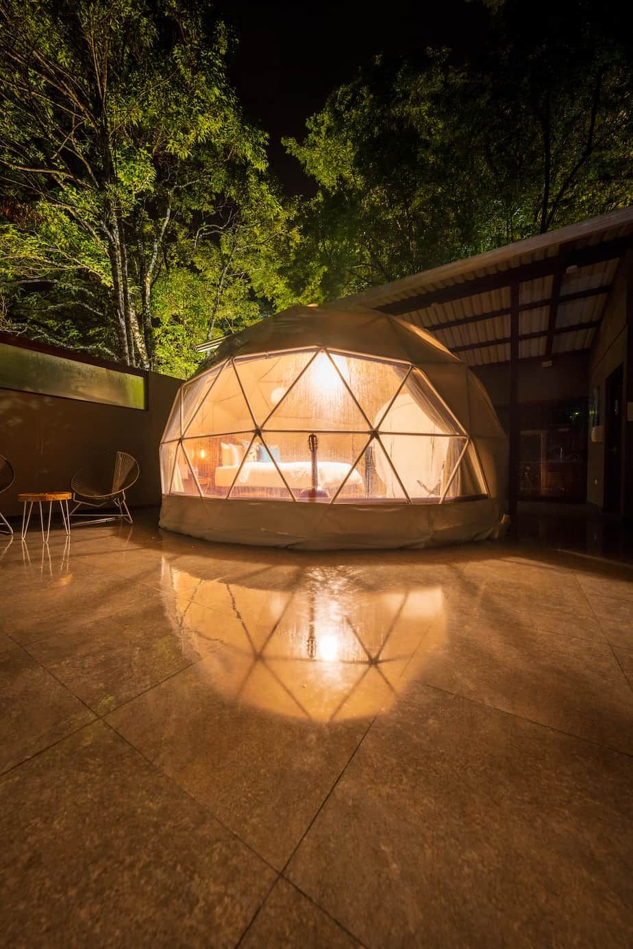 A dome tent with a bed inside of it is lit up at night in costa rica. 