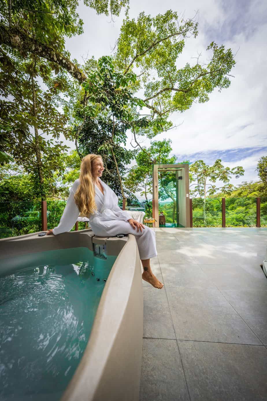 A woman is sitting on the edge of a hot tub in costa rica.