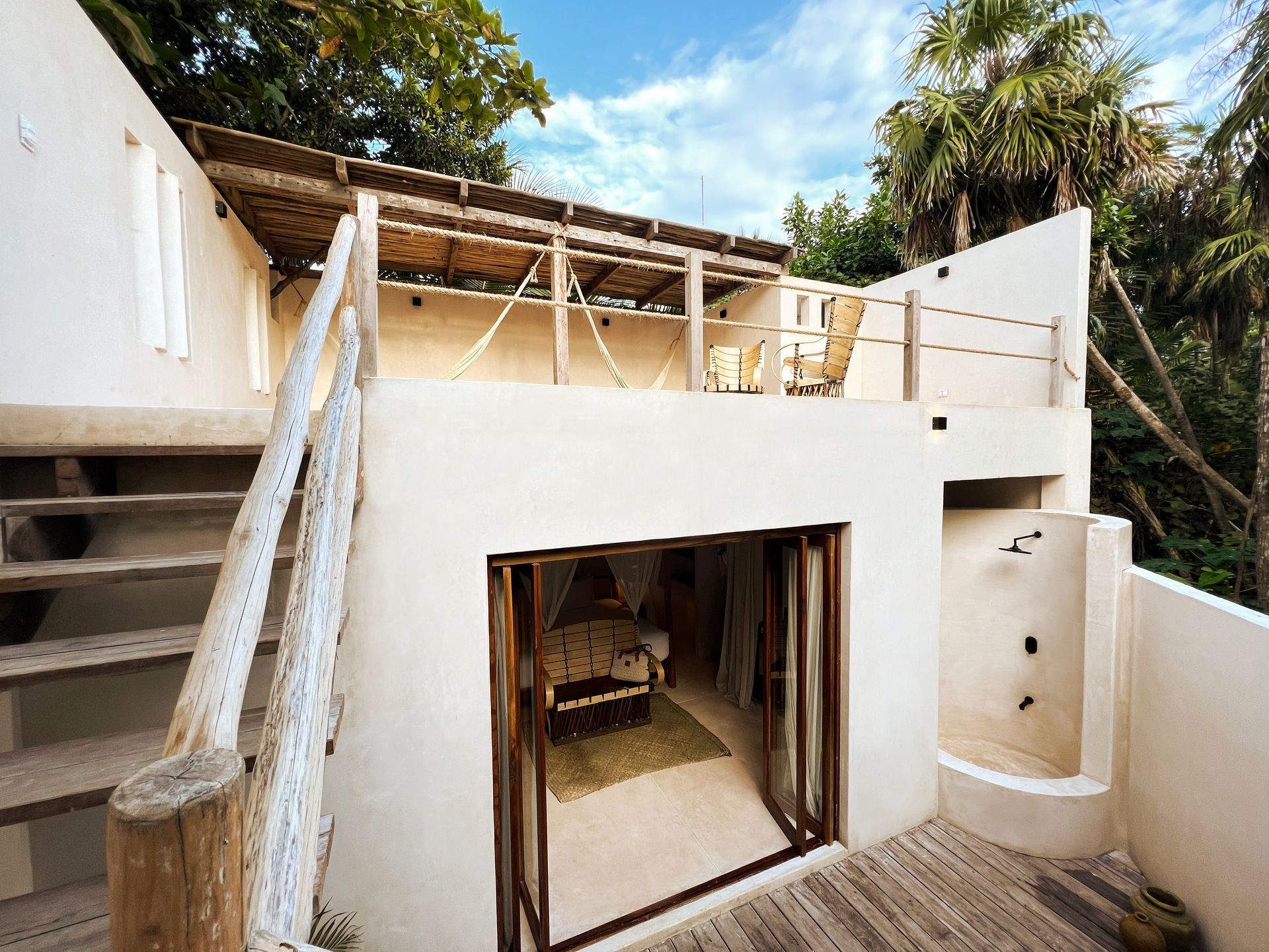 A white house with a balcony and stairs leading up to it at La Valise Tulum hotel in Mexico.