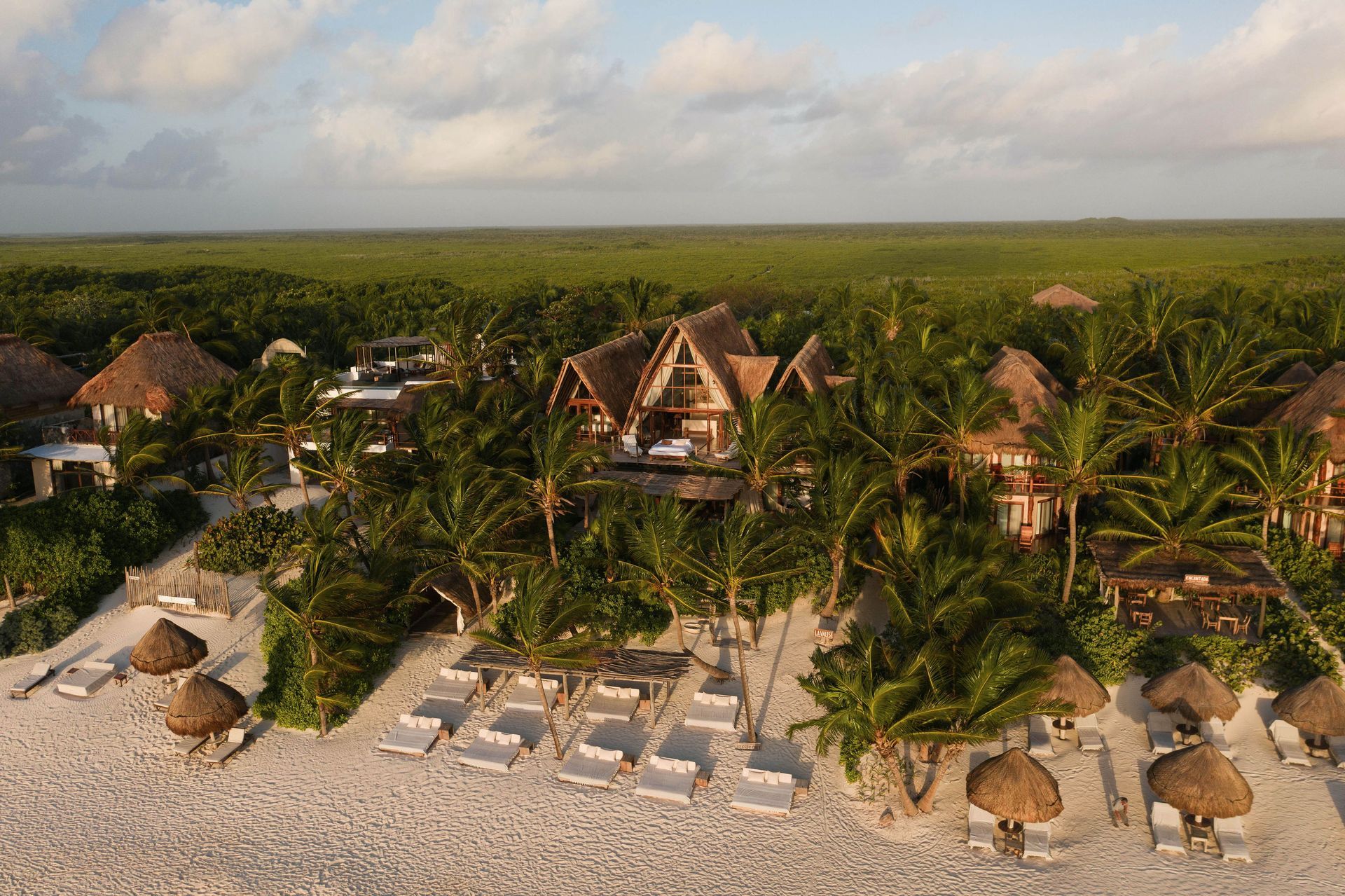 An aerial view of a beach resort surrounded by palm trees at La Valise Tulum hotel in Mexico.