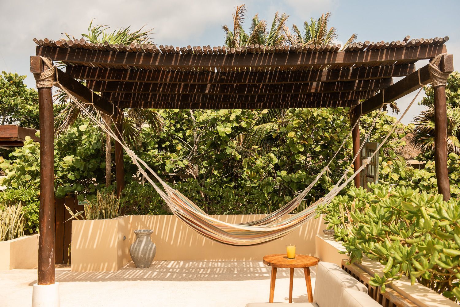 A hammock is sitting under a wooden pergola on a patio at La Zebra hotel in Tulum, Mexico.