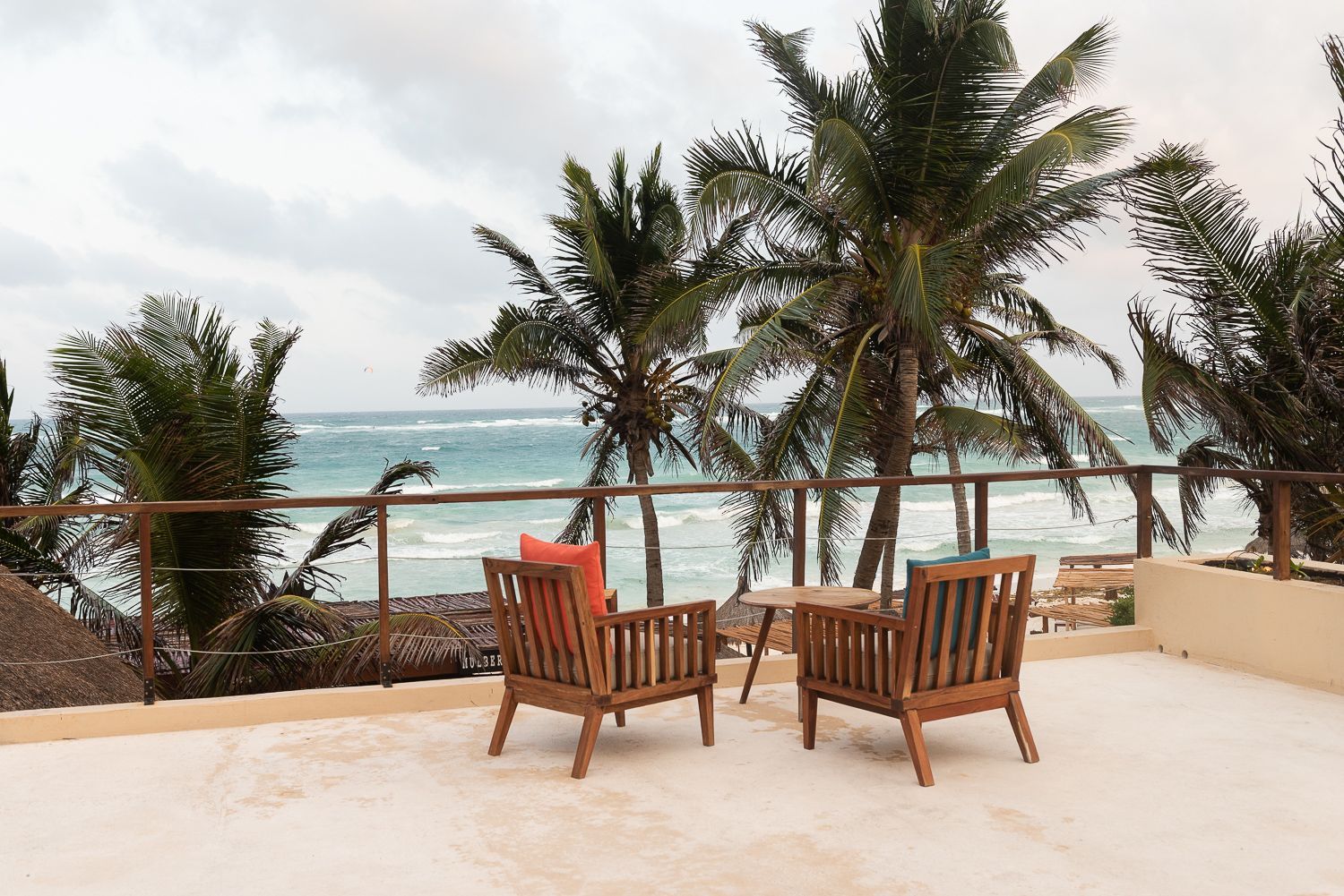 Two chairs and a table on a balcony overlooking the ocean at La Zebra hotel in Tulum, Mexico.