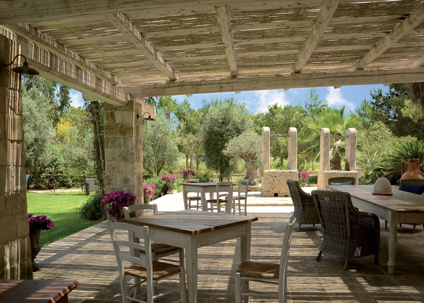 A patio with tables and chairs under a pergola at Naturalis Bio Resort & Spa in Puglia, Italy.