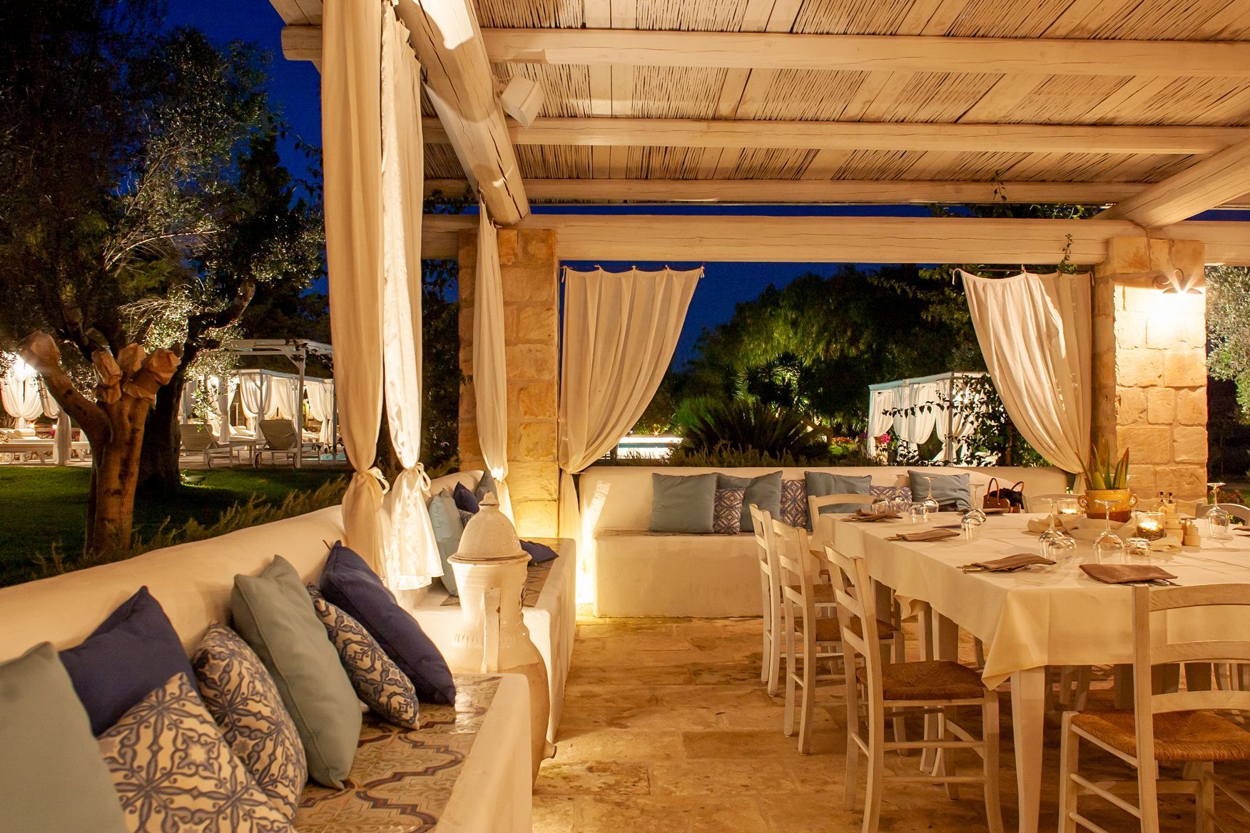 A restaurant with tables and chairs under a canopy at night at Naturalis Bio Resort & Spa in Puglia, Italy.