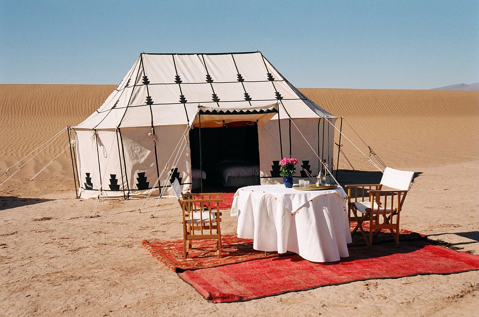 A table and chairs in front of a tent in the desert in Morocco.