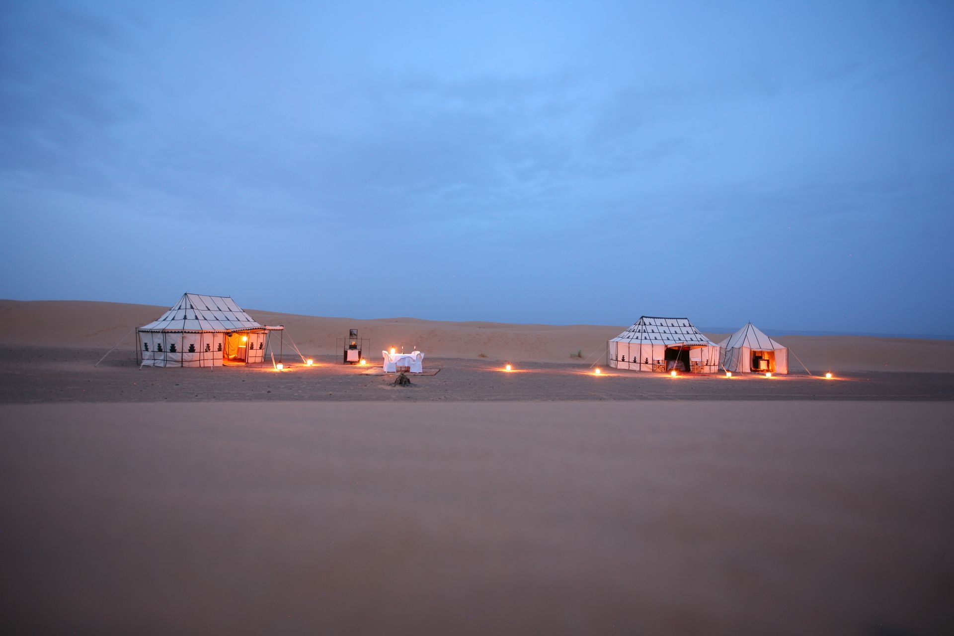 A group of tents are sitting in the middle of a desert in Morocco.