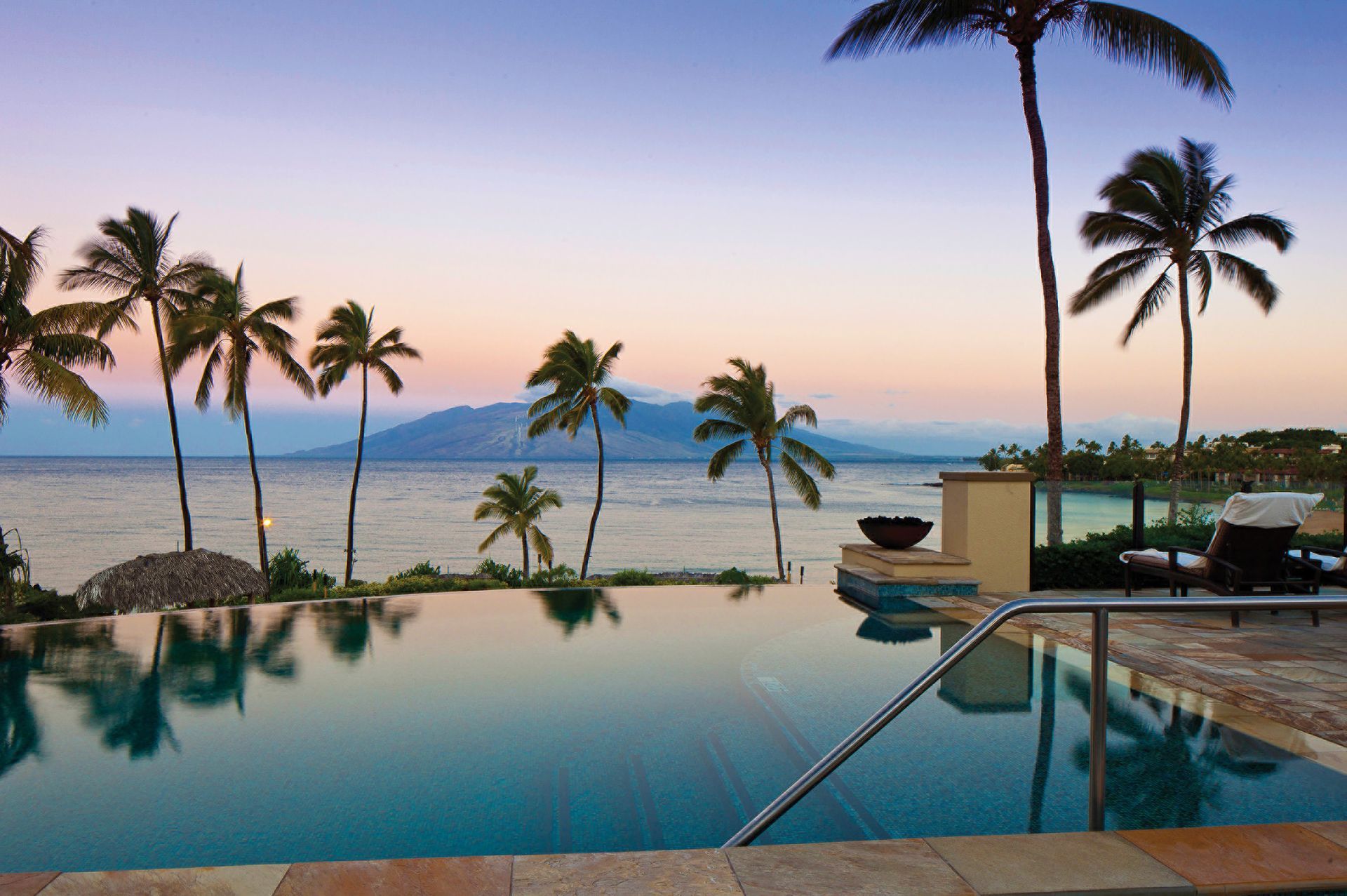 A swimming pool surrounded by palm trees overlooking the ocean of Maui, Hawaii at Four Seasons Hotel