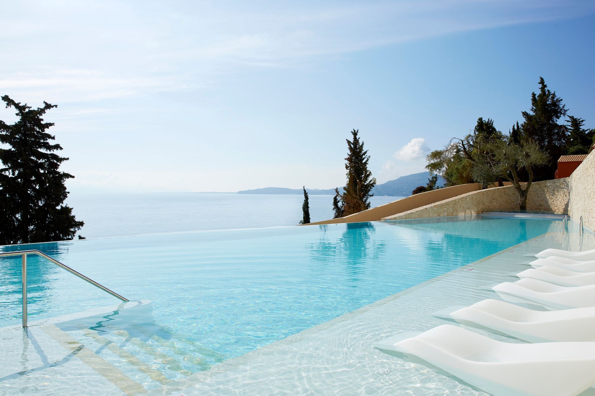 A large swimming pool with a view of the ocean at Nido Hotel, Mar-Bella Collection in Corfu, Greece.