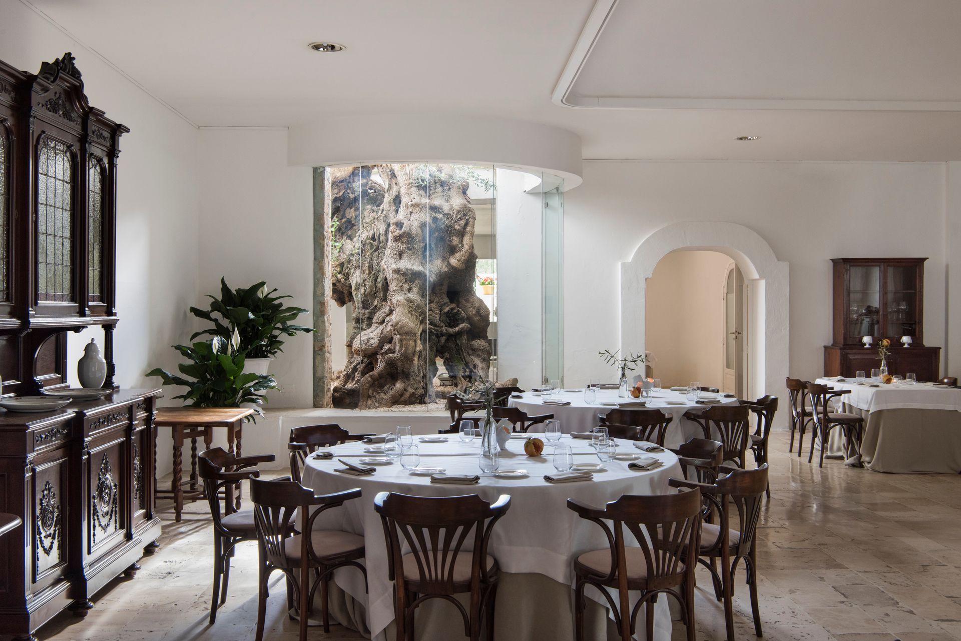 A dining room with tables and chairs and a painting on the wall at Il Melograno Hotel in Puglia, Italy.