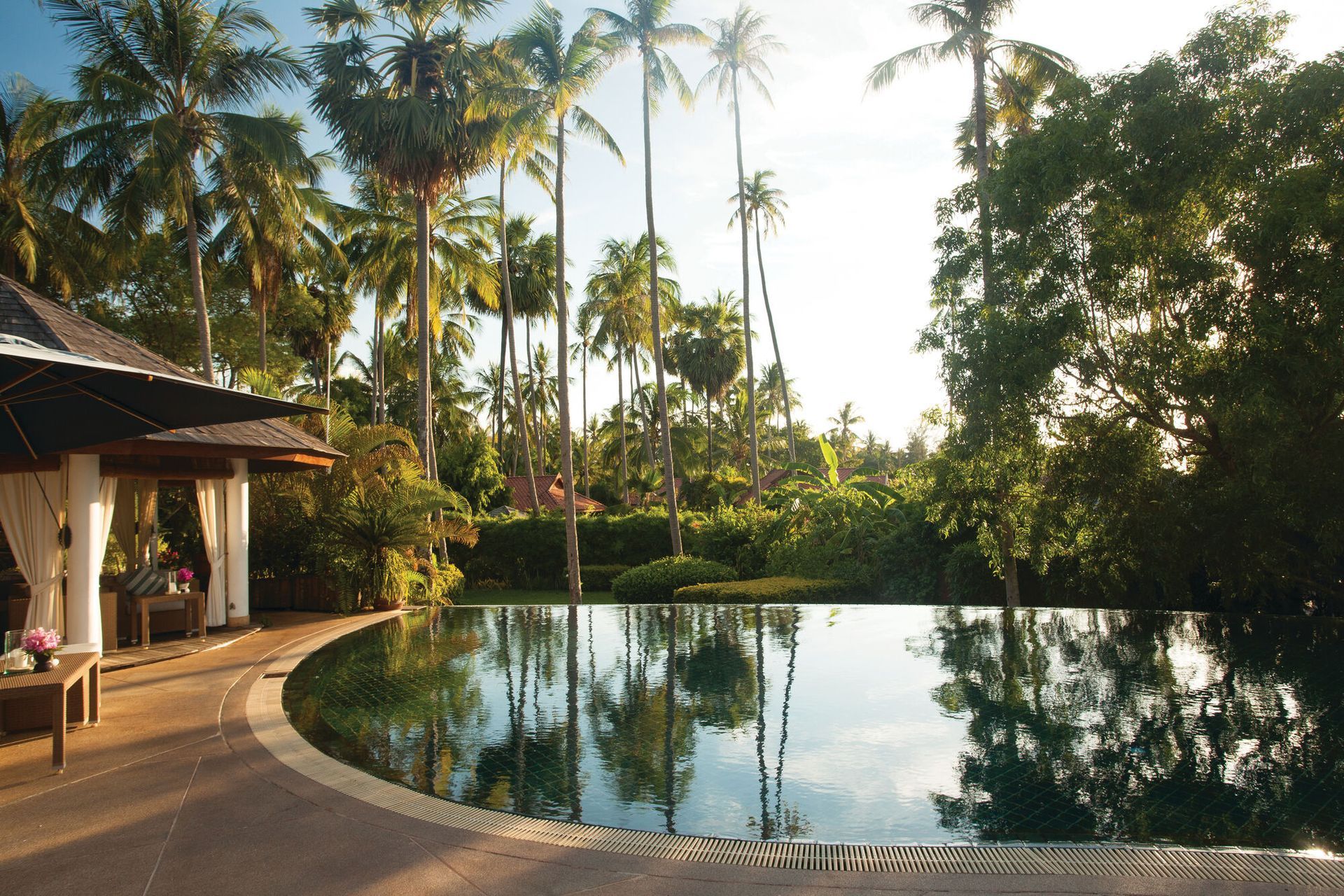 A large swimming pool surrounded by palm trees in Koh Samui, Thailand  at Belmond Hotel.