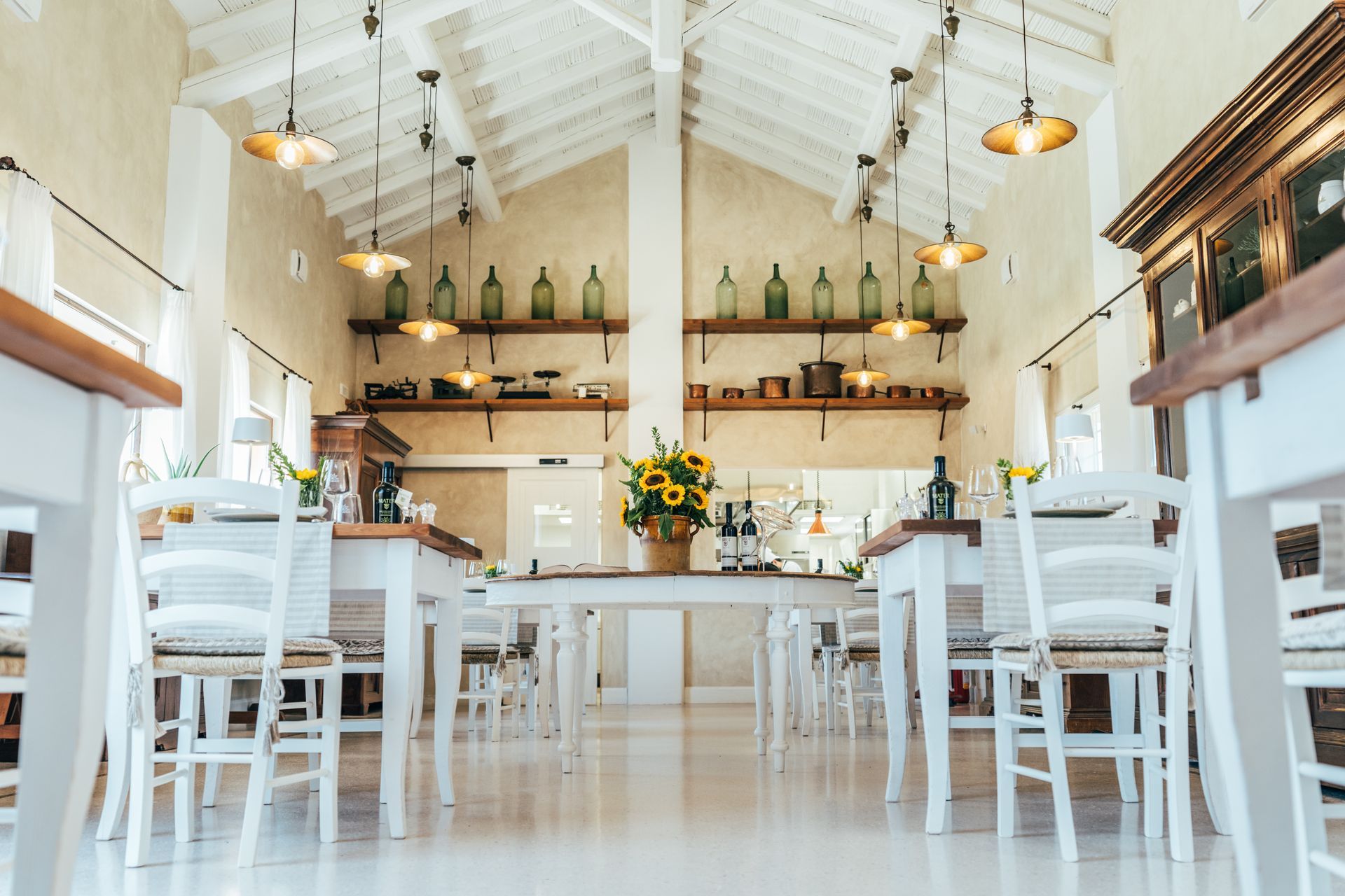 A dining room with tables and chairs and a vase of flowers on the table at Naturalis Bio Resort & Spa in Puglia, Italy.