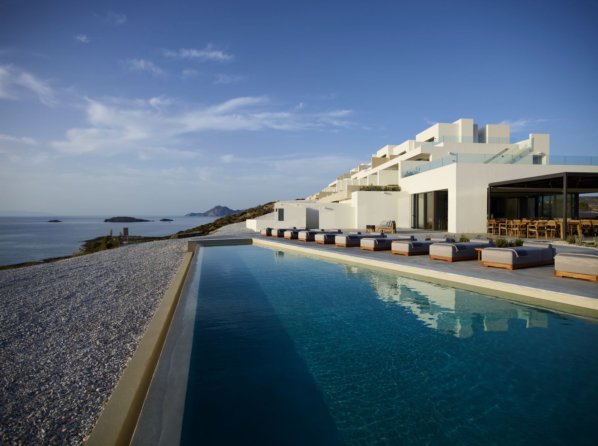 A large swimming pool in front of a white building overlooking the ocean