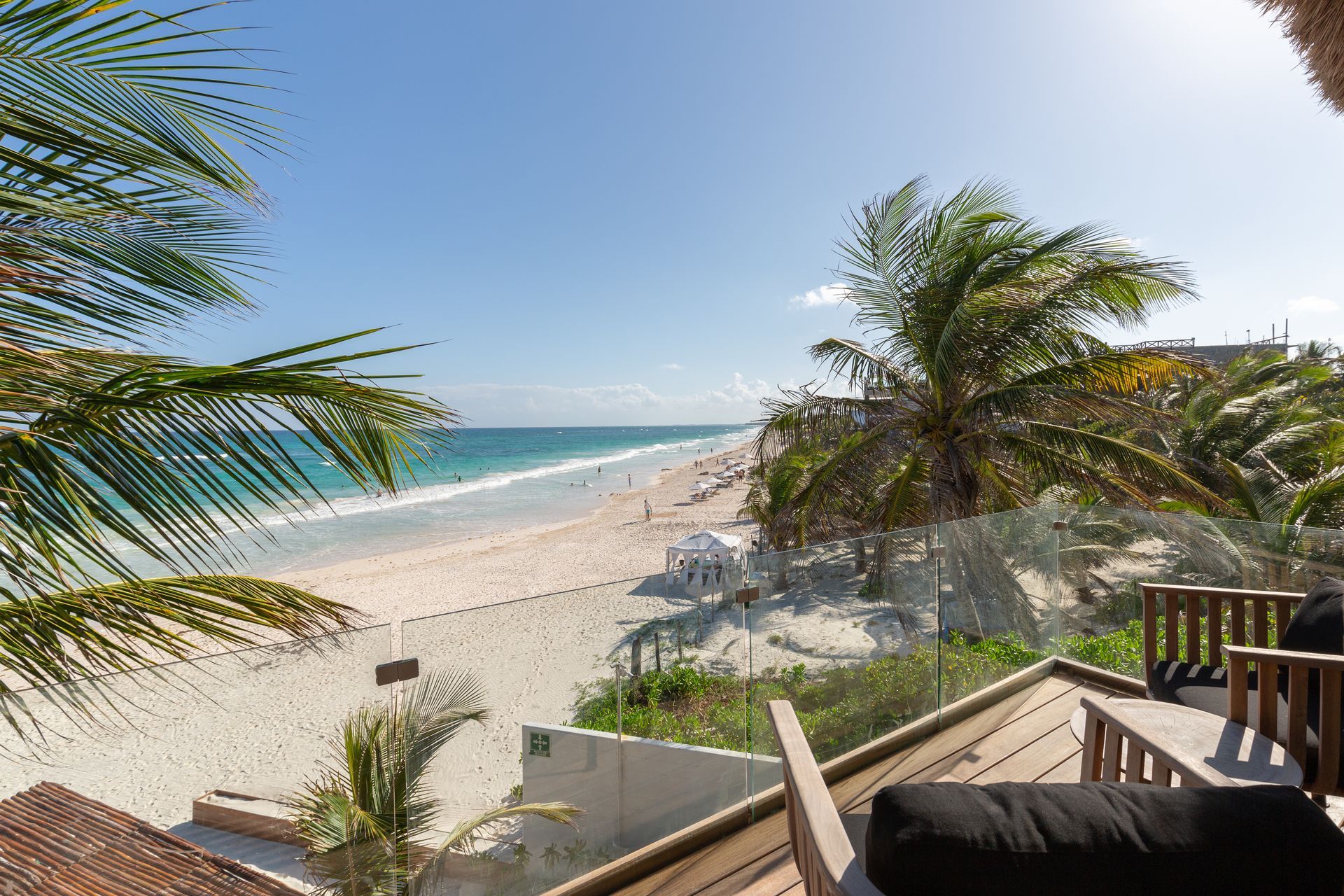 A view of a beach from a balcony with palm trees at TAGO Tulum Hotel in Mexico.