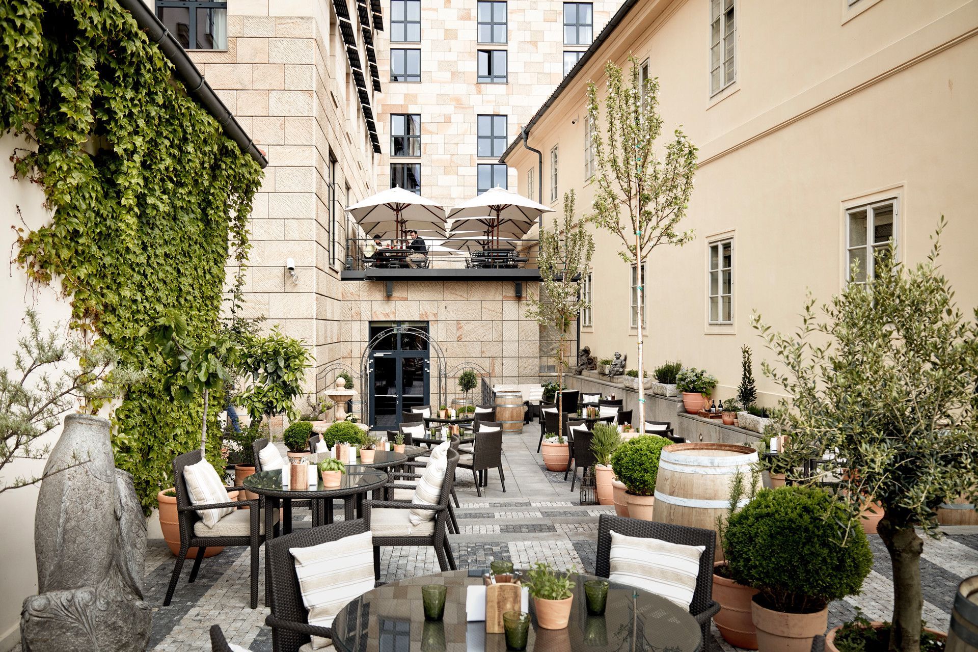 A courtyard with tables and chairs in front of a building in Prague at Four Seasons Hotel. 