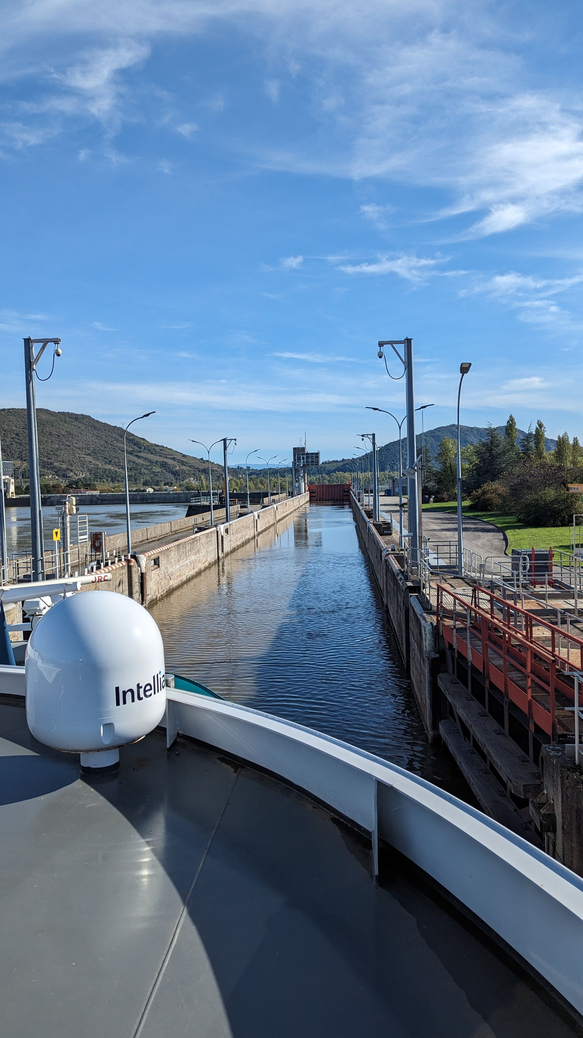 A boat entering a canal lock; water between concrete walls, blue sky overhead.