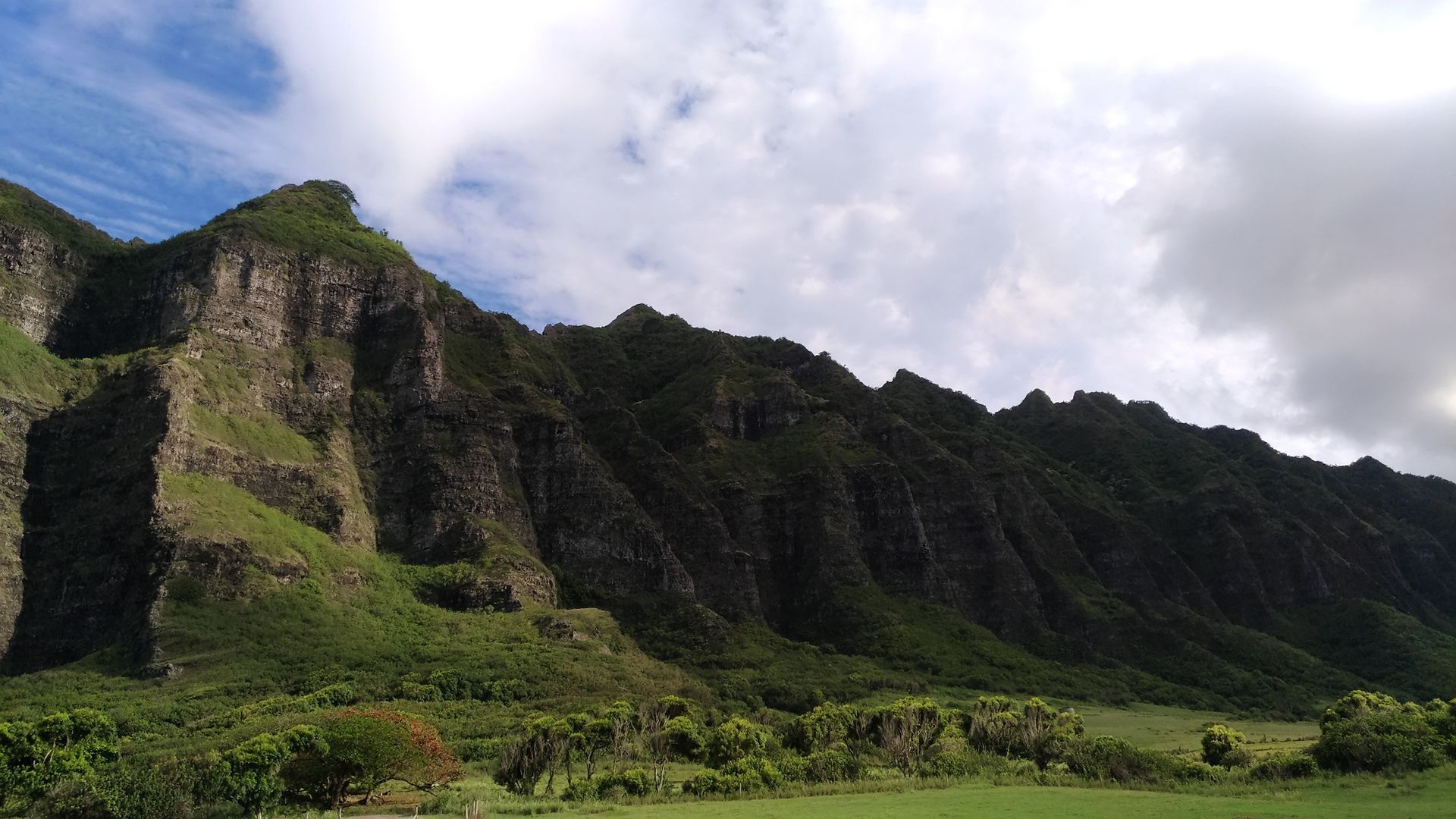 Jagged, green mountain range under a cloudy sky.