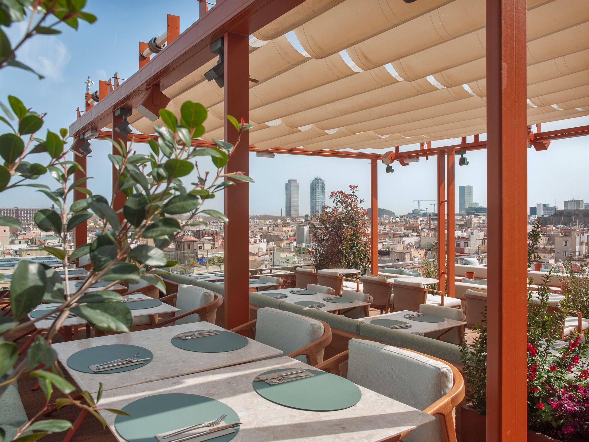 A restaurant with tables and chairs under a canopy with a view of Barcelona, Spain at the Grand Hotel Central.