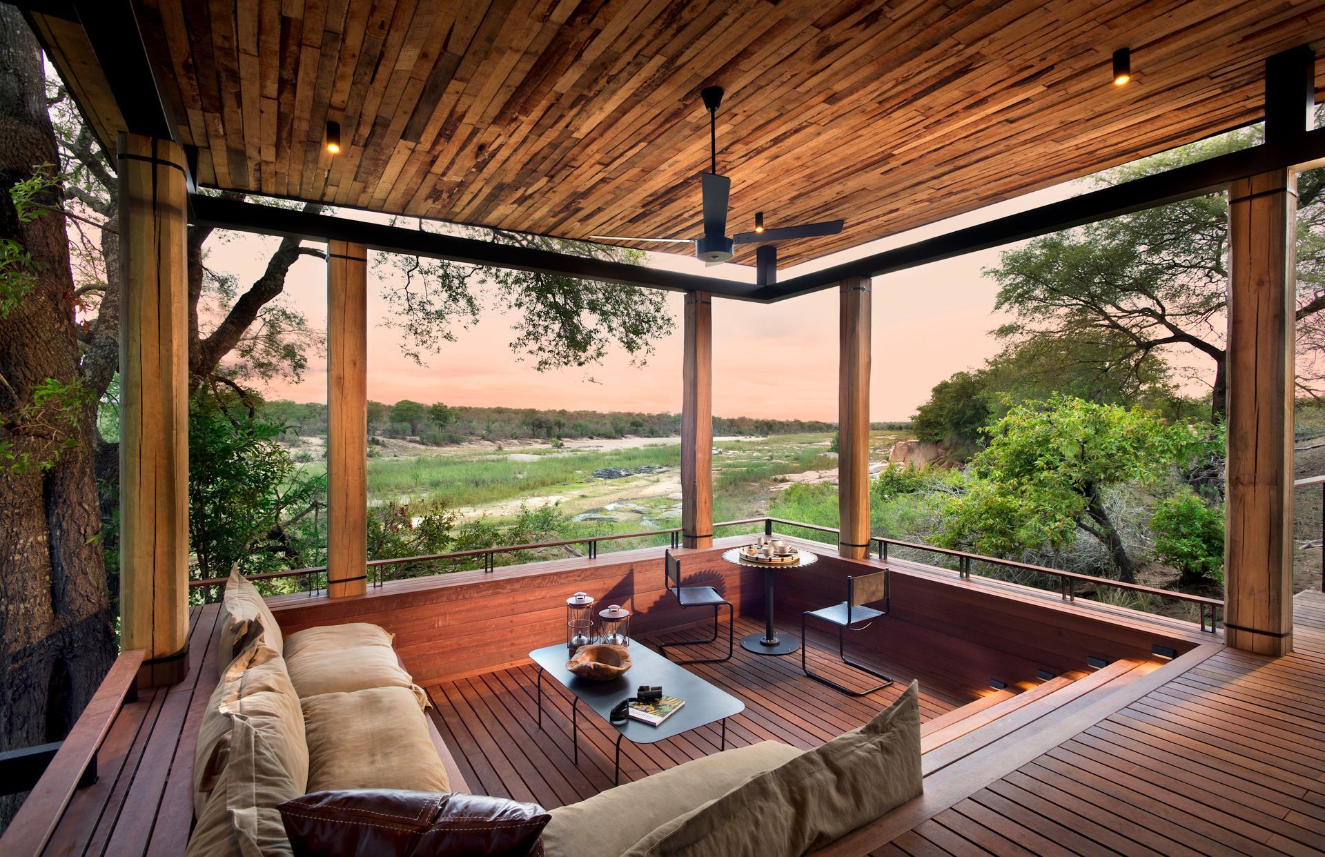 A living room with a view of a field and trees at a lodge in Africa.