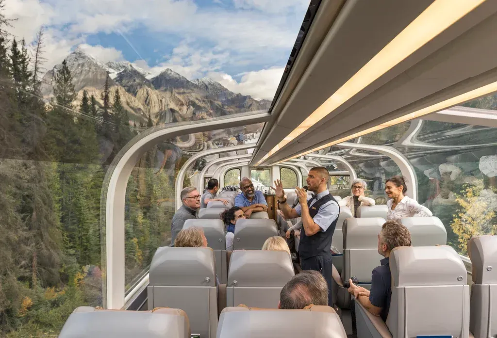 A man is taking a picture of a group of people on a Rocky Mountaineer train.