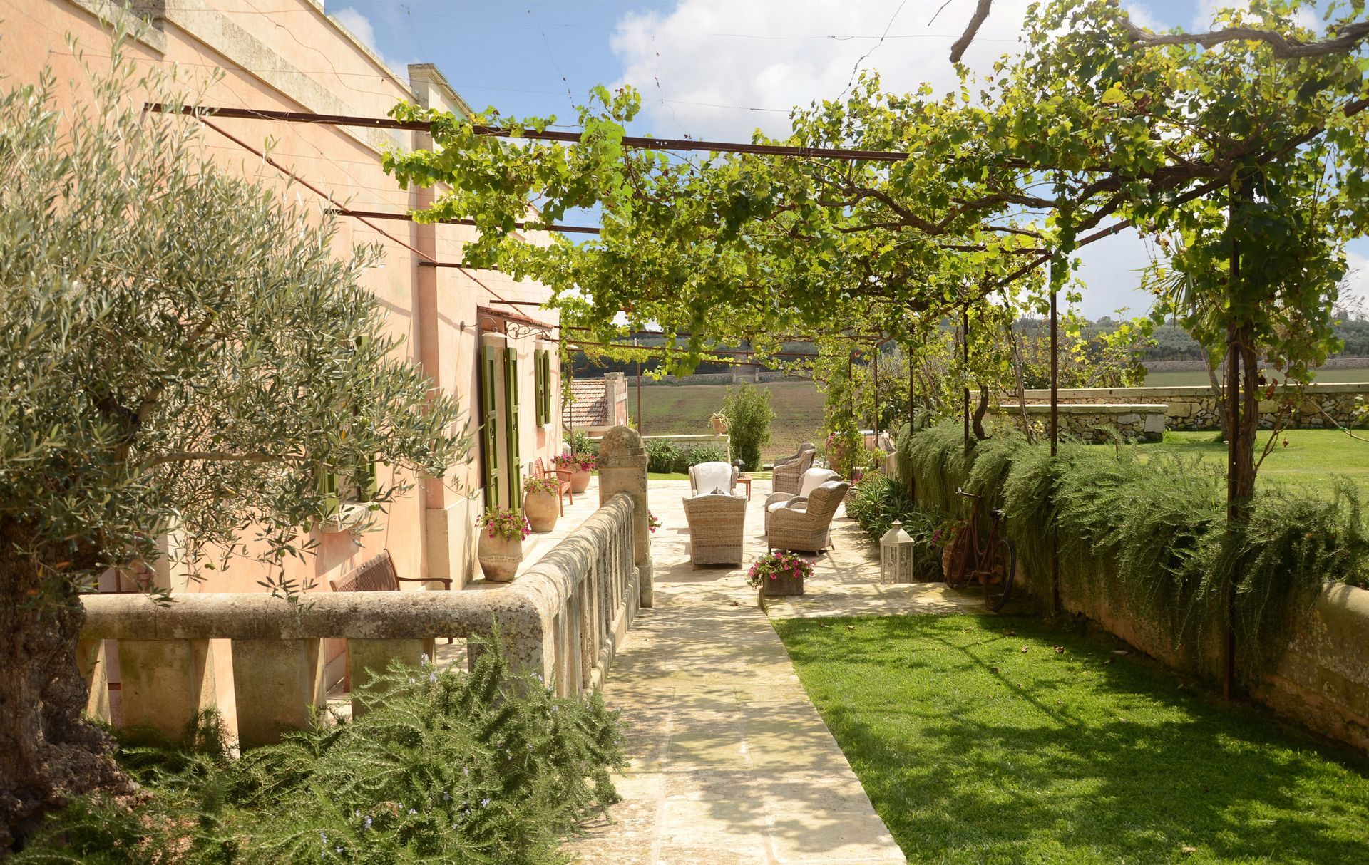 A patio with a pergola and chairs in front of a house at Naturalis Bio Resort & Spa in Puglia, Italy.