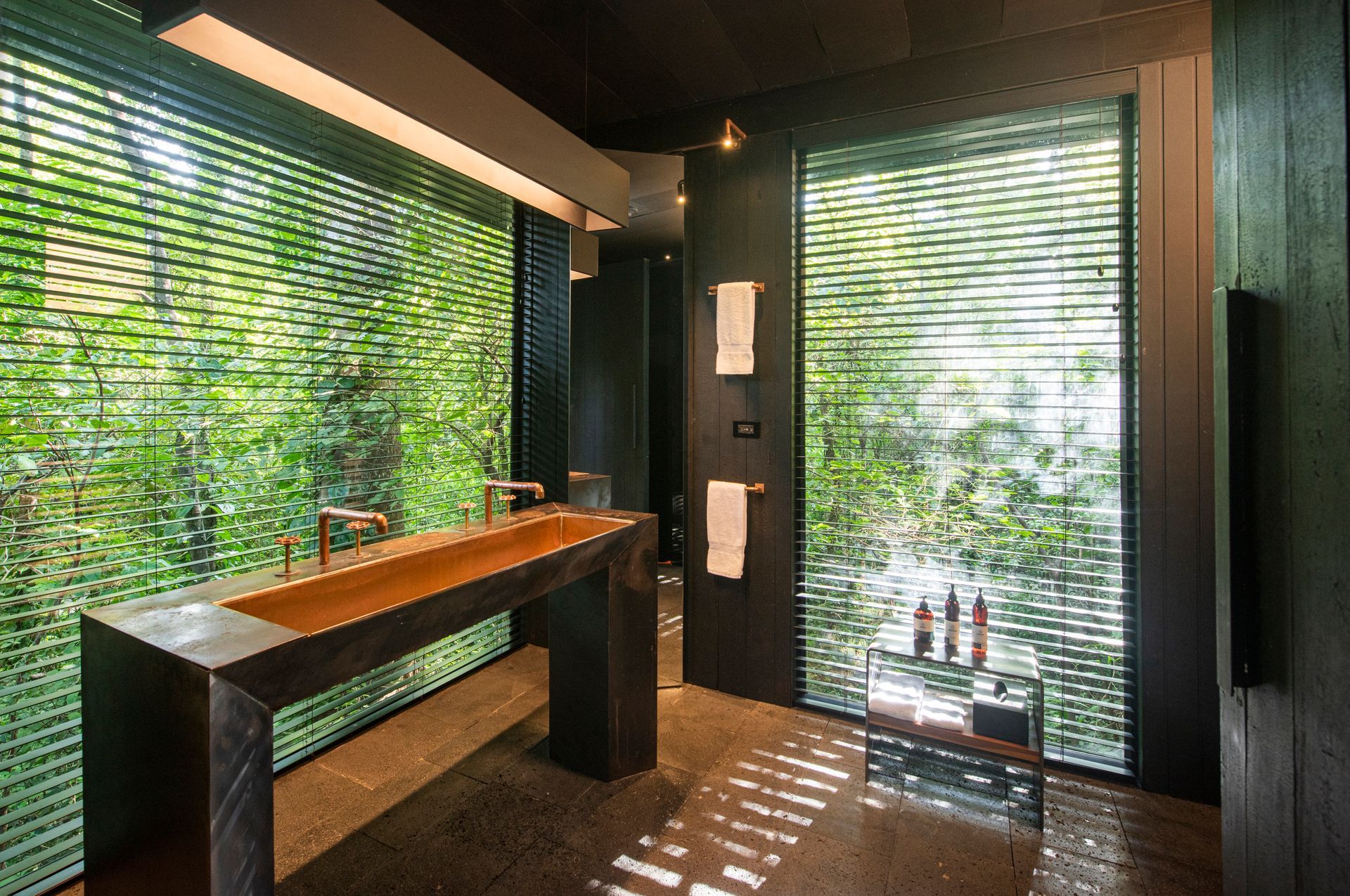 A bathroom with a sink and a window with blinds in a tree house in Costa Rica.