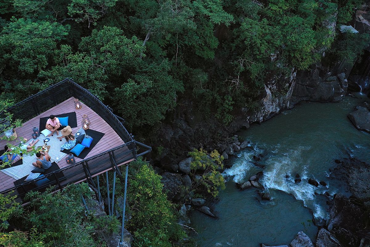 A group of people are sitting on a deck overlooking a river in Costa Rica.