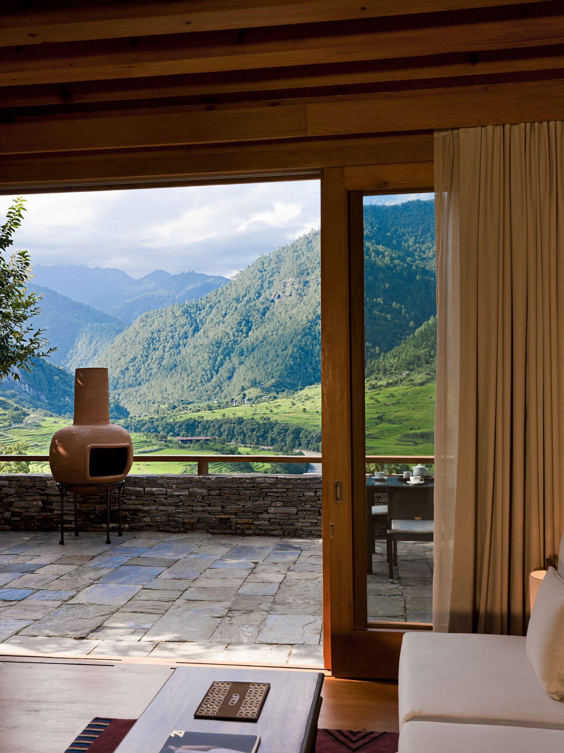 A living room with a view of the mountain range of Punakha, Bhutan at Como Hotel.
