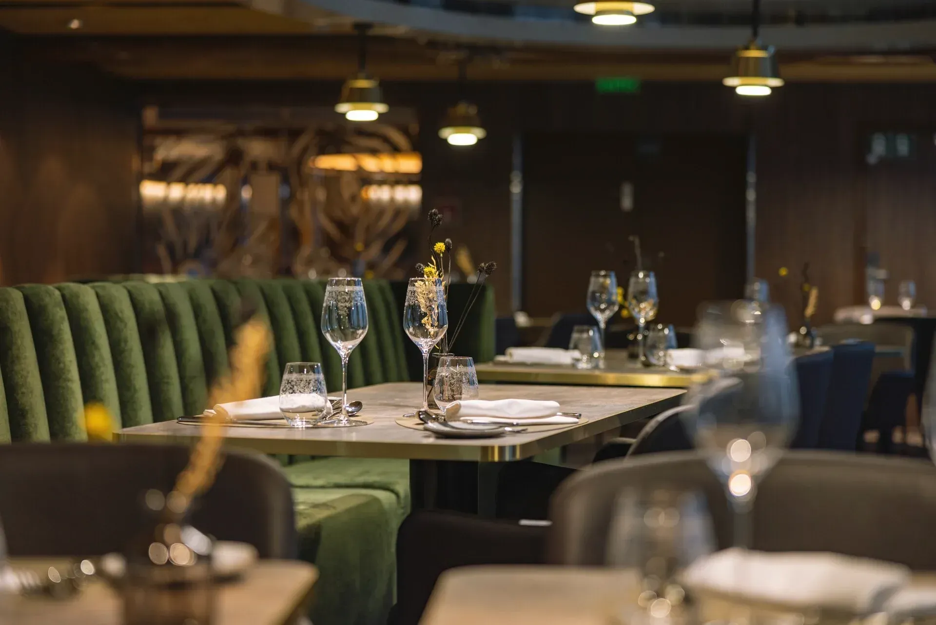 A restaurant with tables and chairs set for dinner and wine glasses on them on Hurtigruten's MS Trollfjord cruise ship.