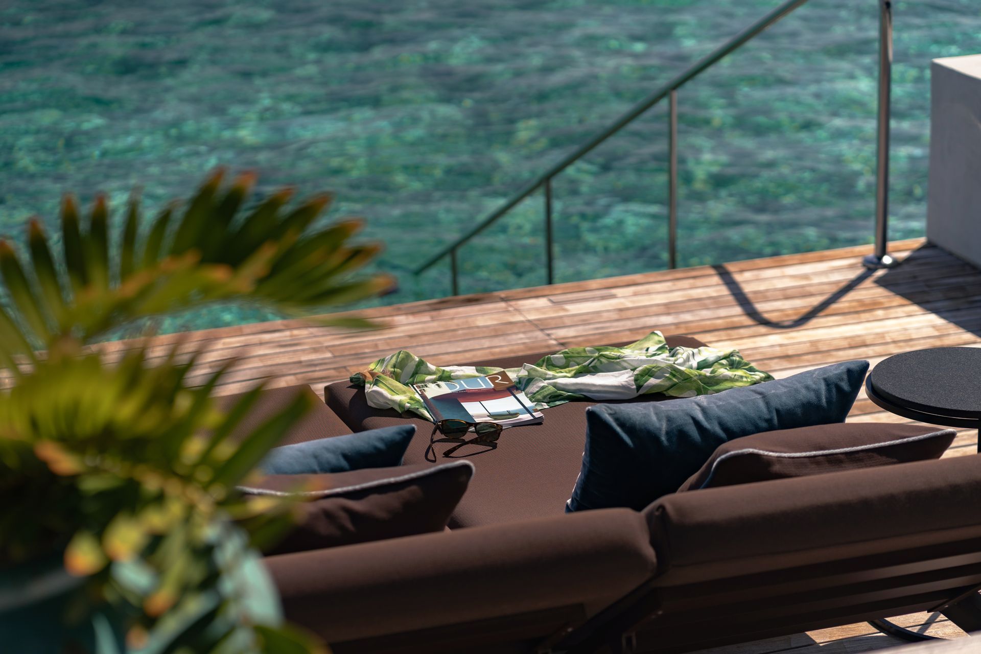 A couch is sitting on a wooden deck at an overwater bungalow at velaa resort in the Maldives. 