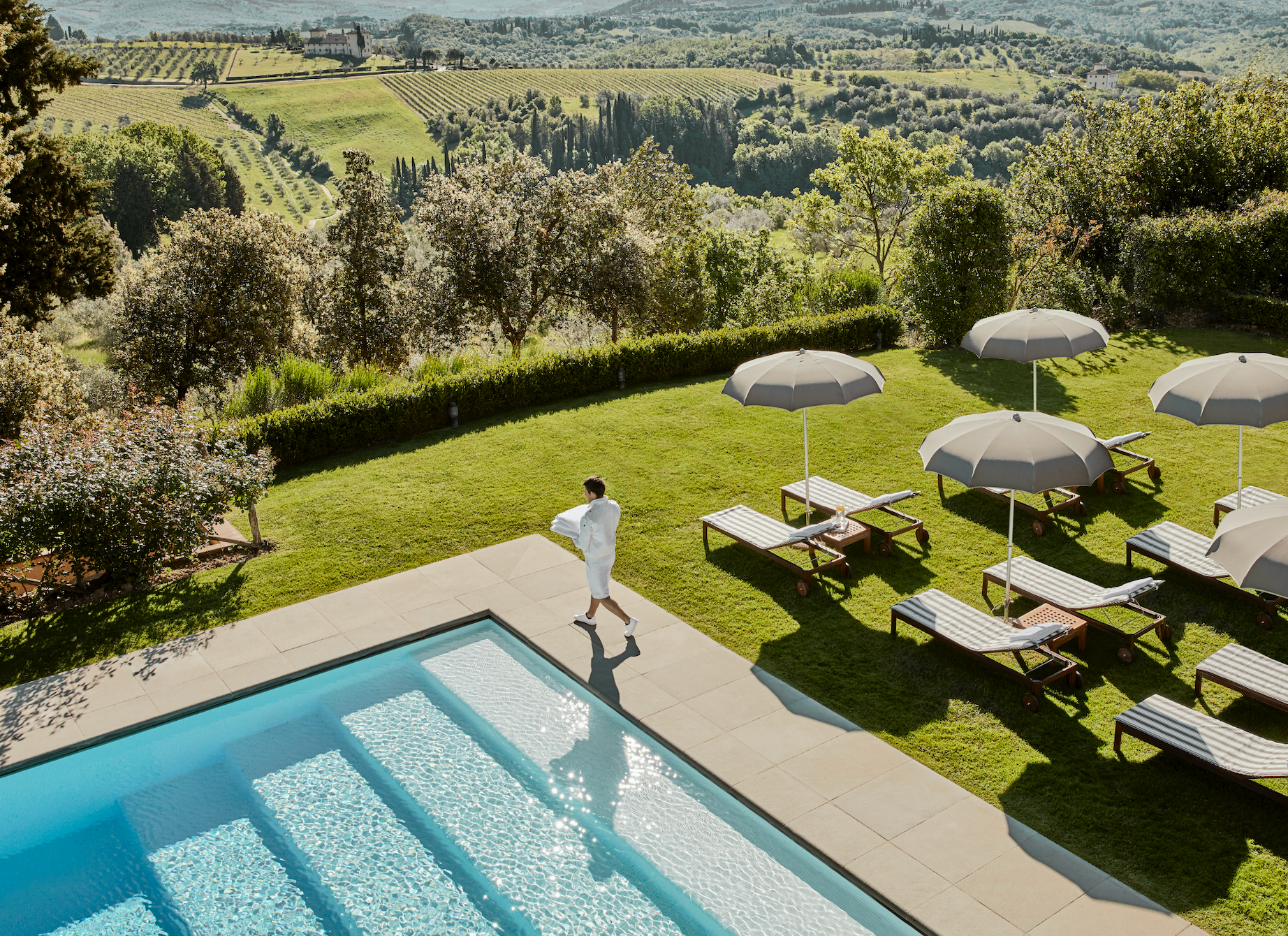 A man in a bathrobe is standing next to a swimming pool in Tuscany, Italy at Como Hotel.