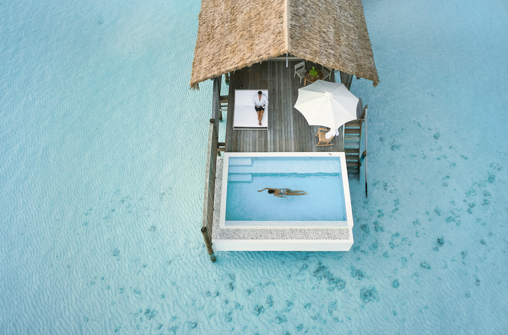 An aerial view of a dock with a swimming pool in the middle of the ocean.