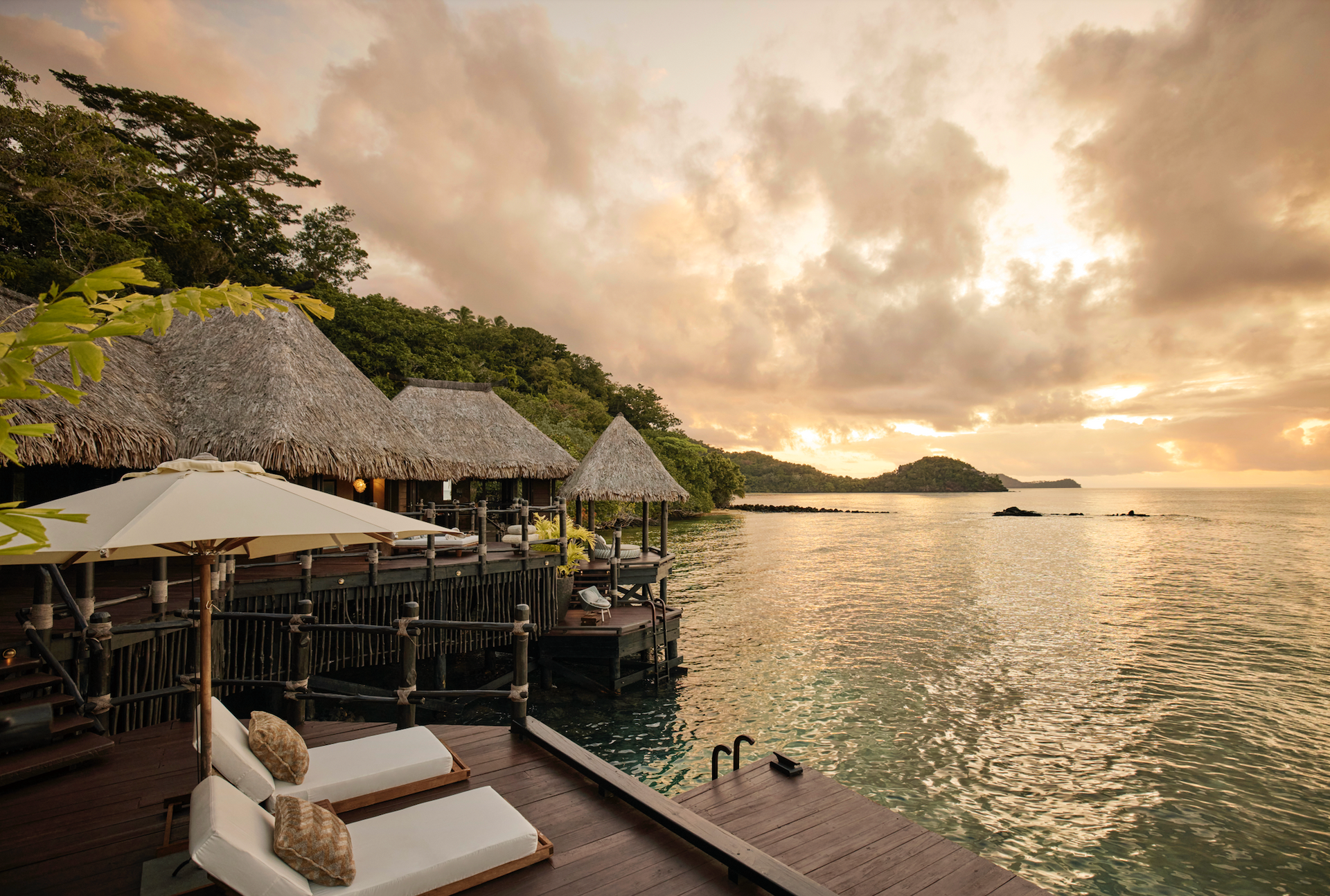 A dock with chairs and umbrellas overlooking a body of water at villa in Fiji.