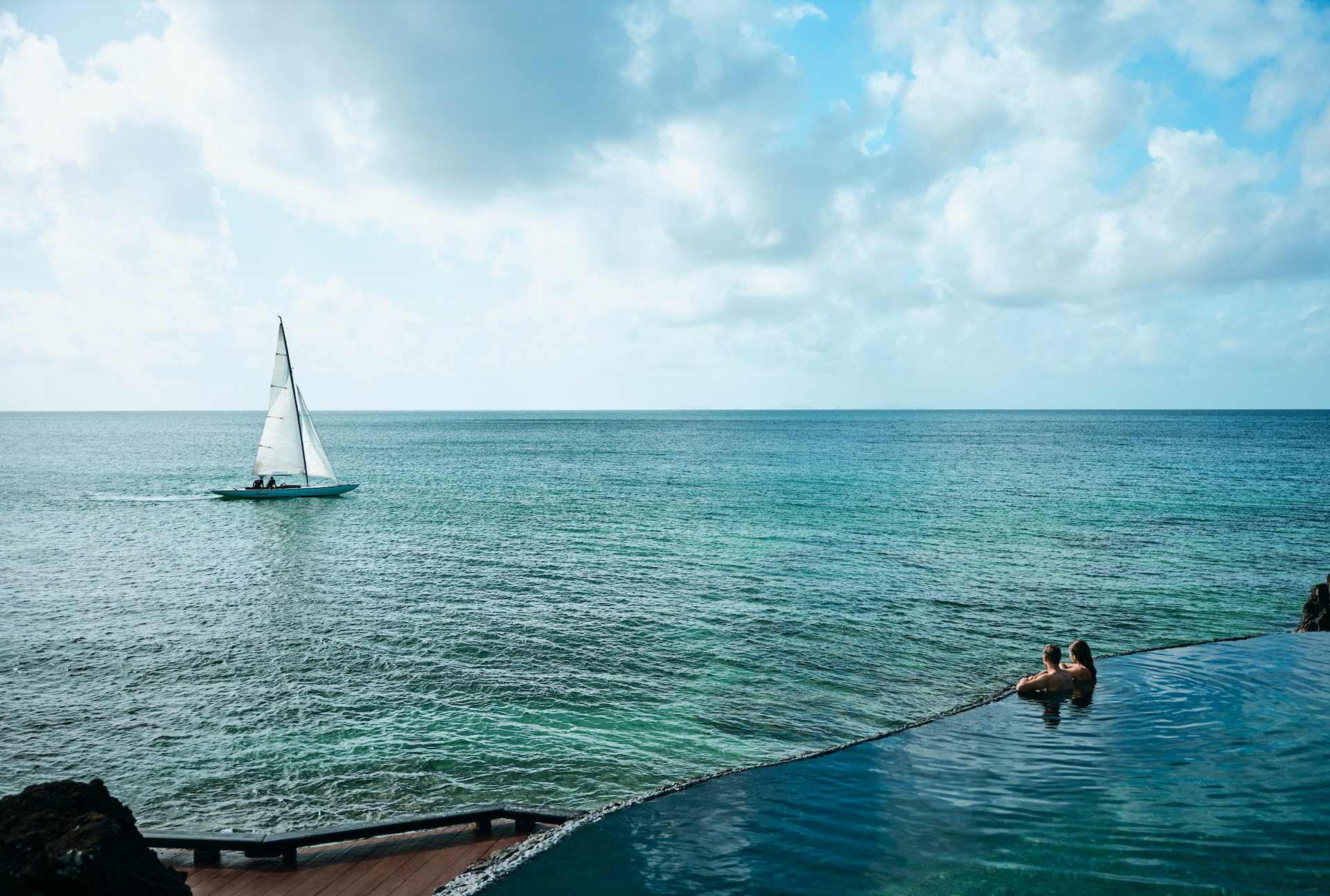 A sailboat is floating in the ocean near a swimming pool at villa in Fiji.