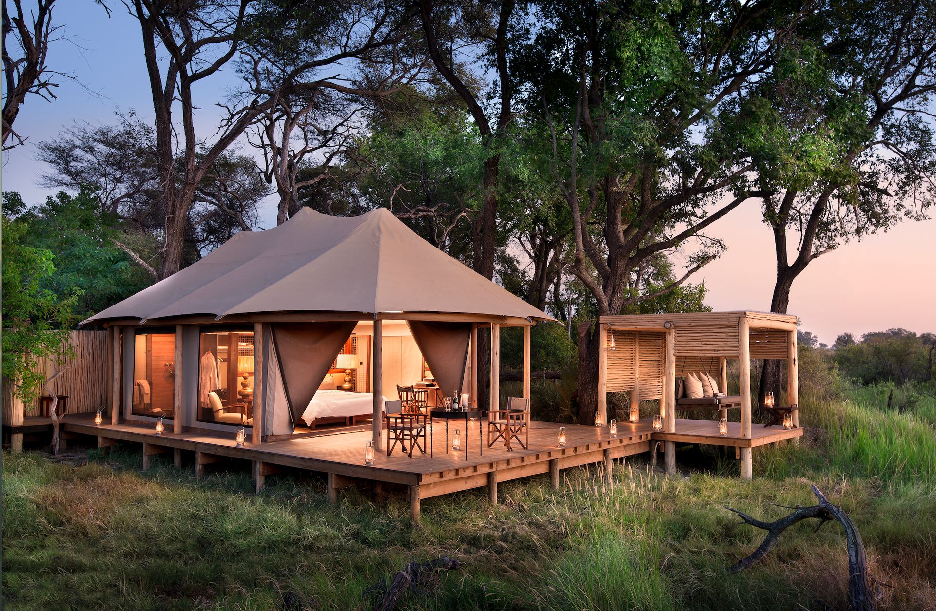 A large tent with a deck in the middle of a field at a camp in Africa.