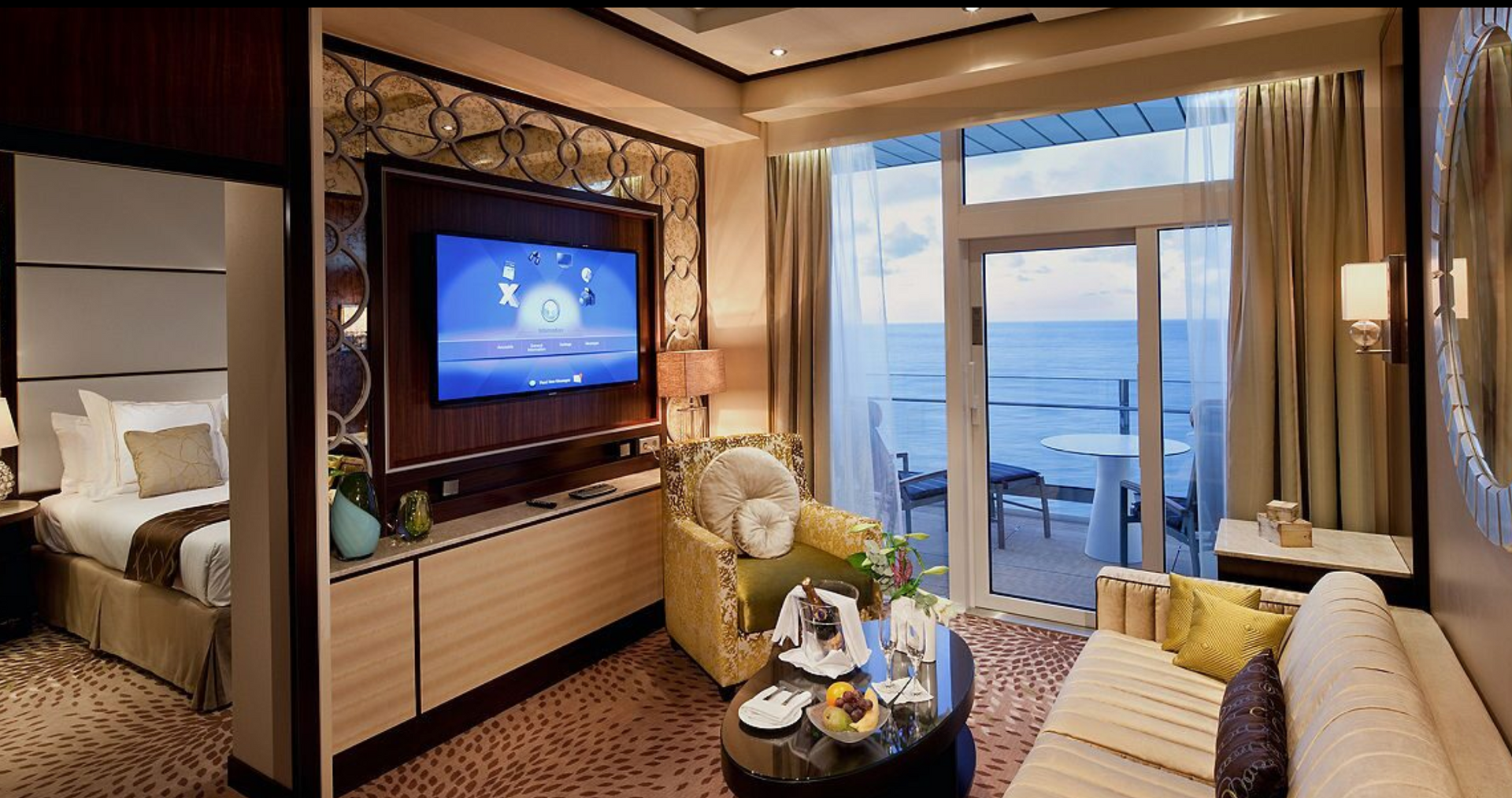 A living room with a couch , chair , table and television on the Celebrity Reflection cruise ship.