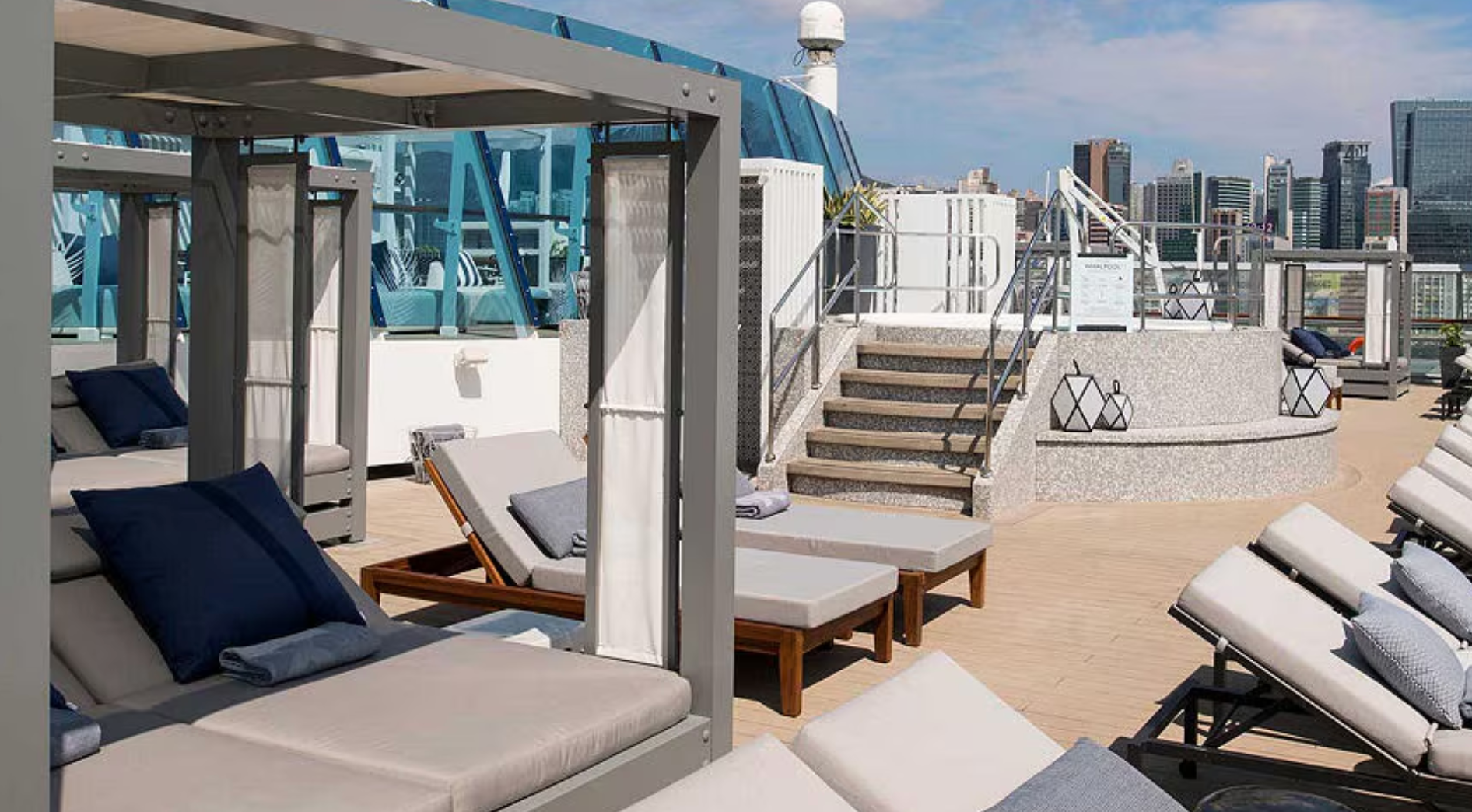 A row of lounge chairs sitting on top of a sandy beach on the Celebrity Summit cruise ship.