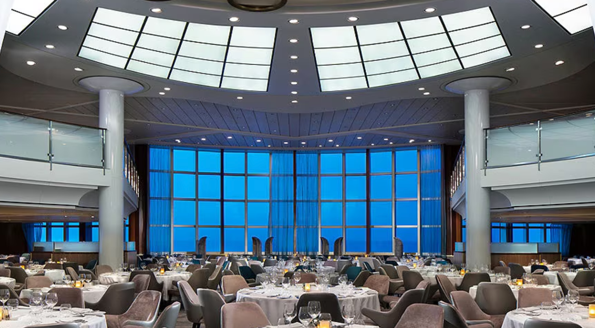 A large room with tables and chairs and a large window on the Celebrity Summit cruise ship.