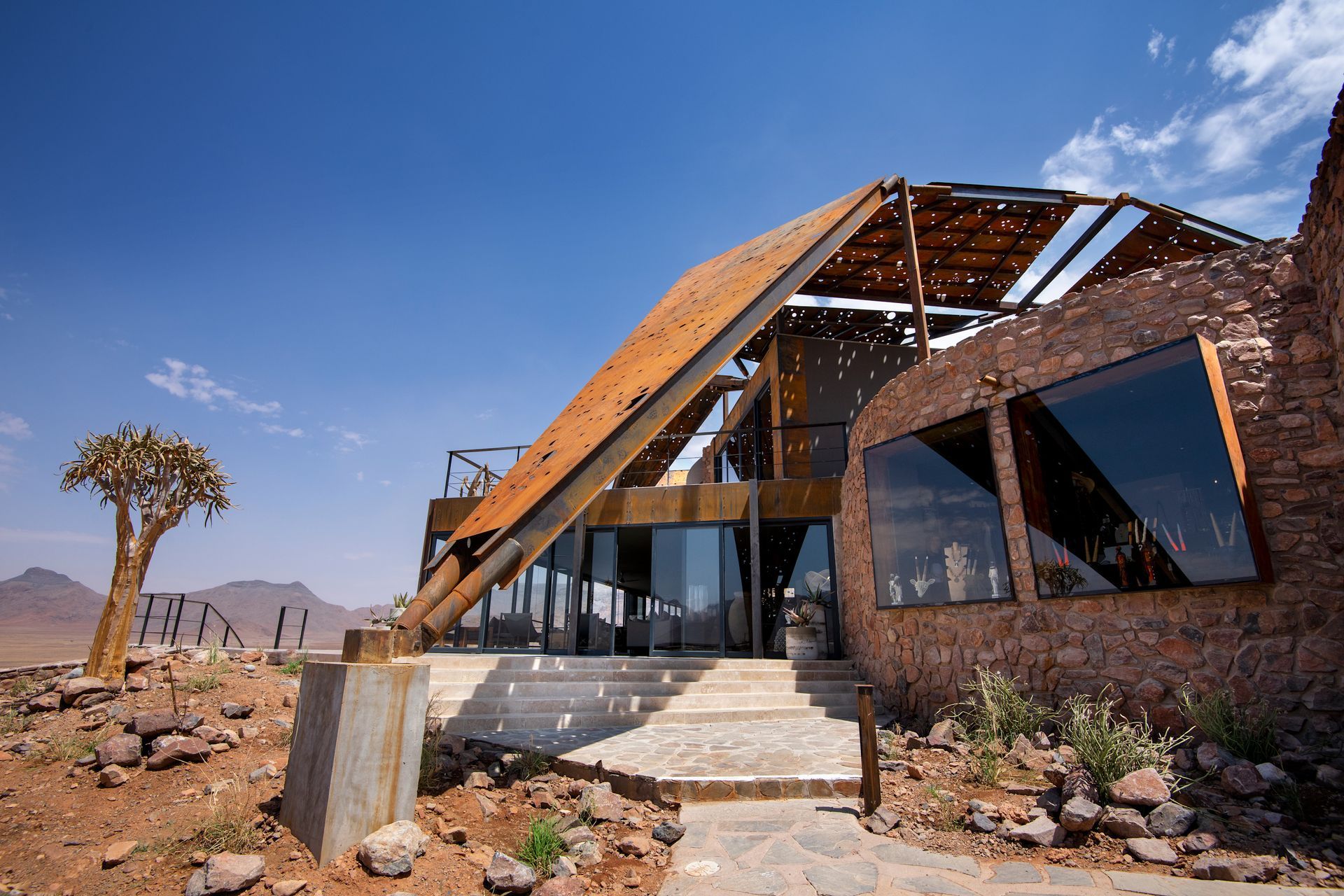 A large brick lodge with a wooden roof in the middle of the desert in Africa.