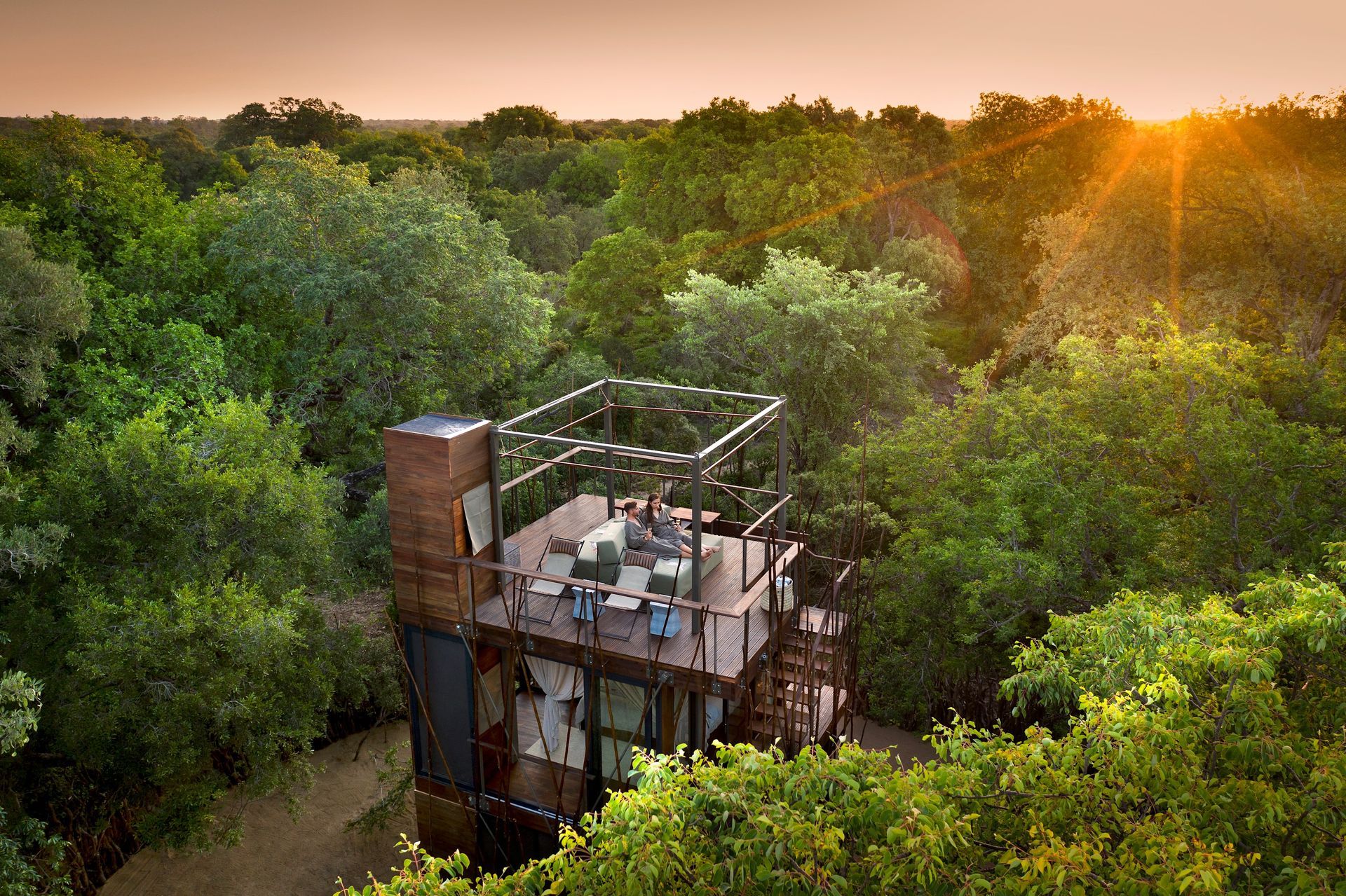 An aerial view of a tree house in the middle of a forest in Africa.