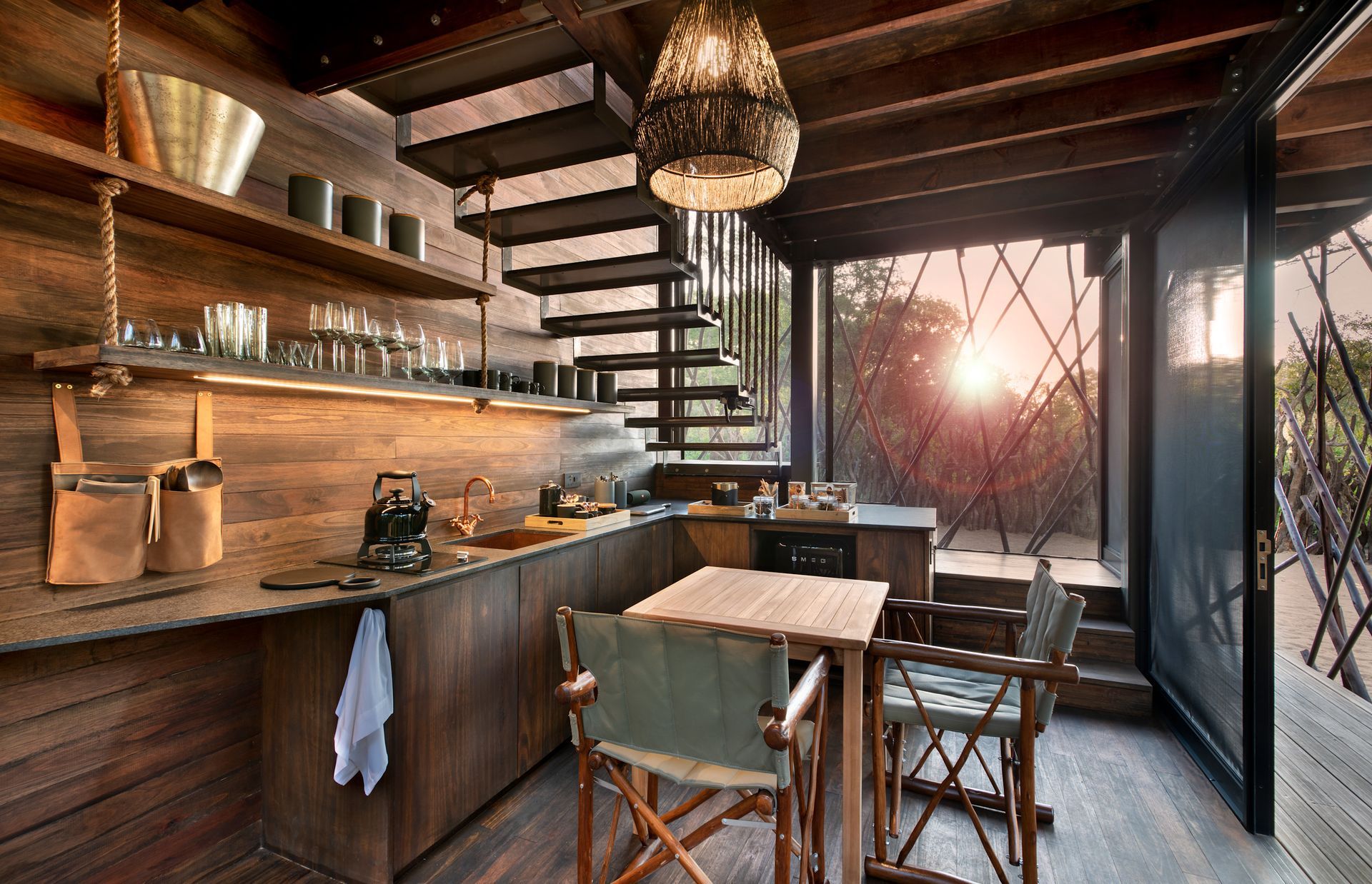 A kitchen with a table and chairs and stairs at a tree house in Africa.