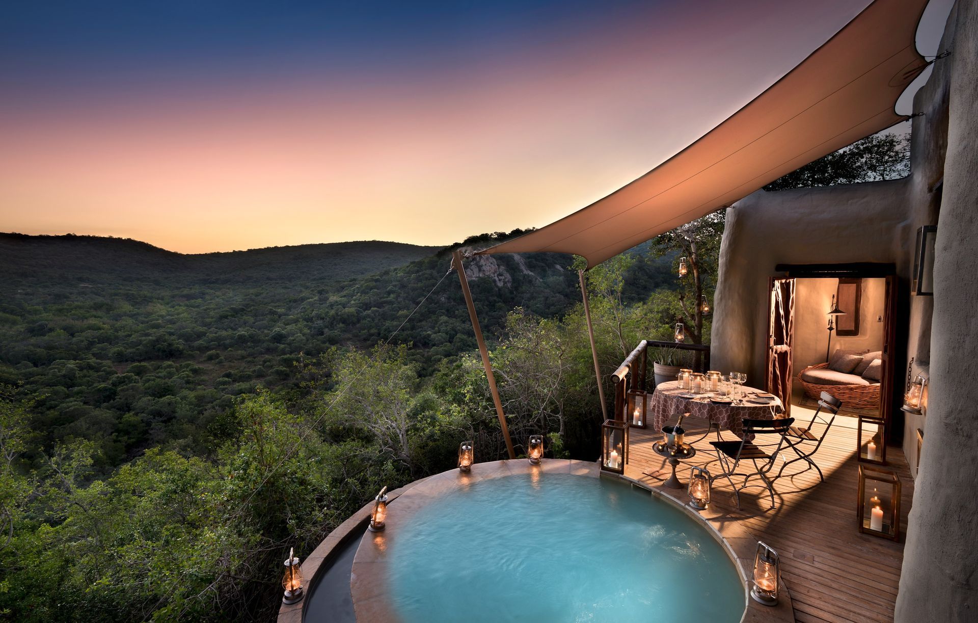 A large swimming pool with a view of a forest at a lodge in Africa.