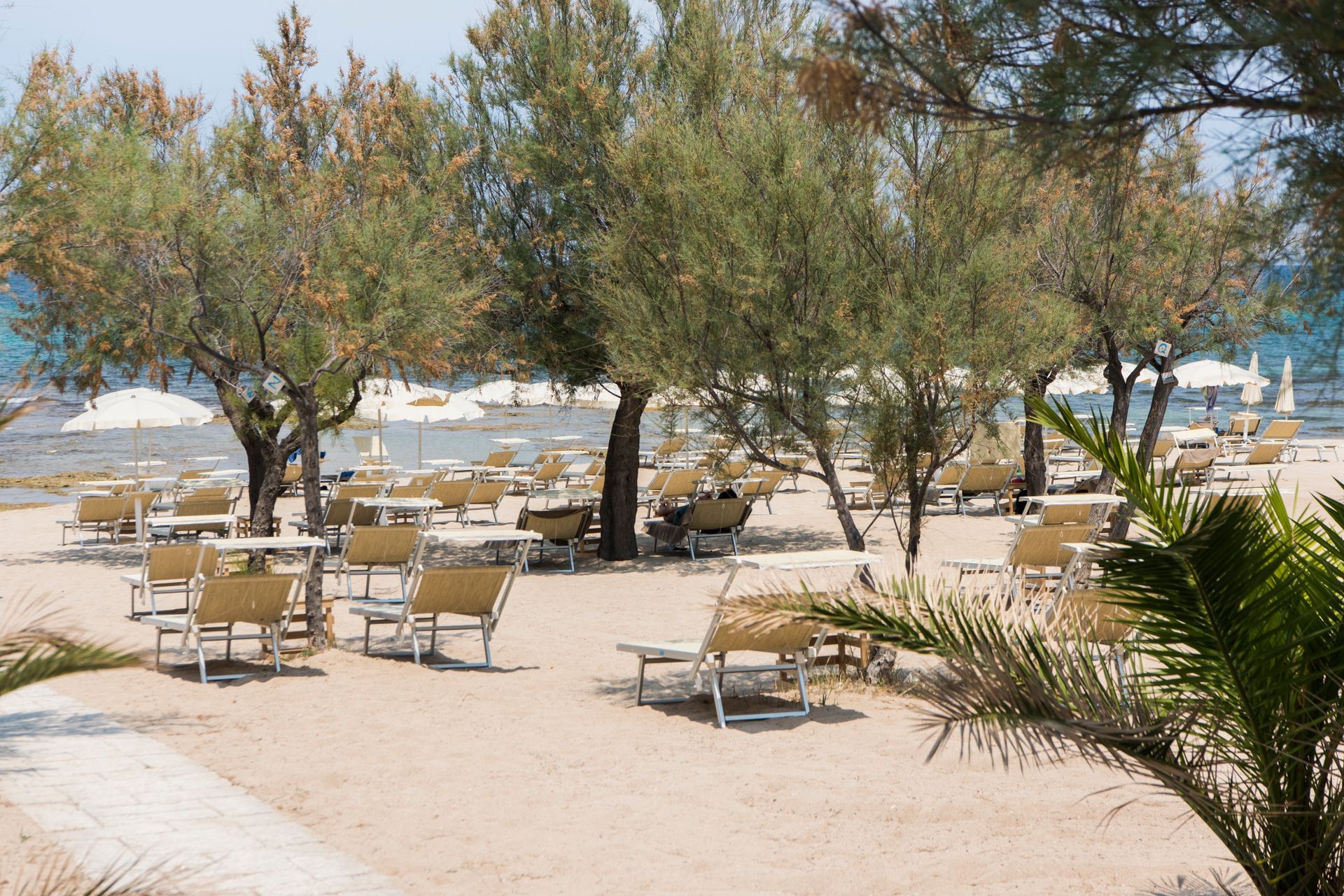 There are many chairs and tables on the beach at Il Melograno Hotel in Puglia, Italy.