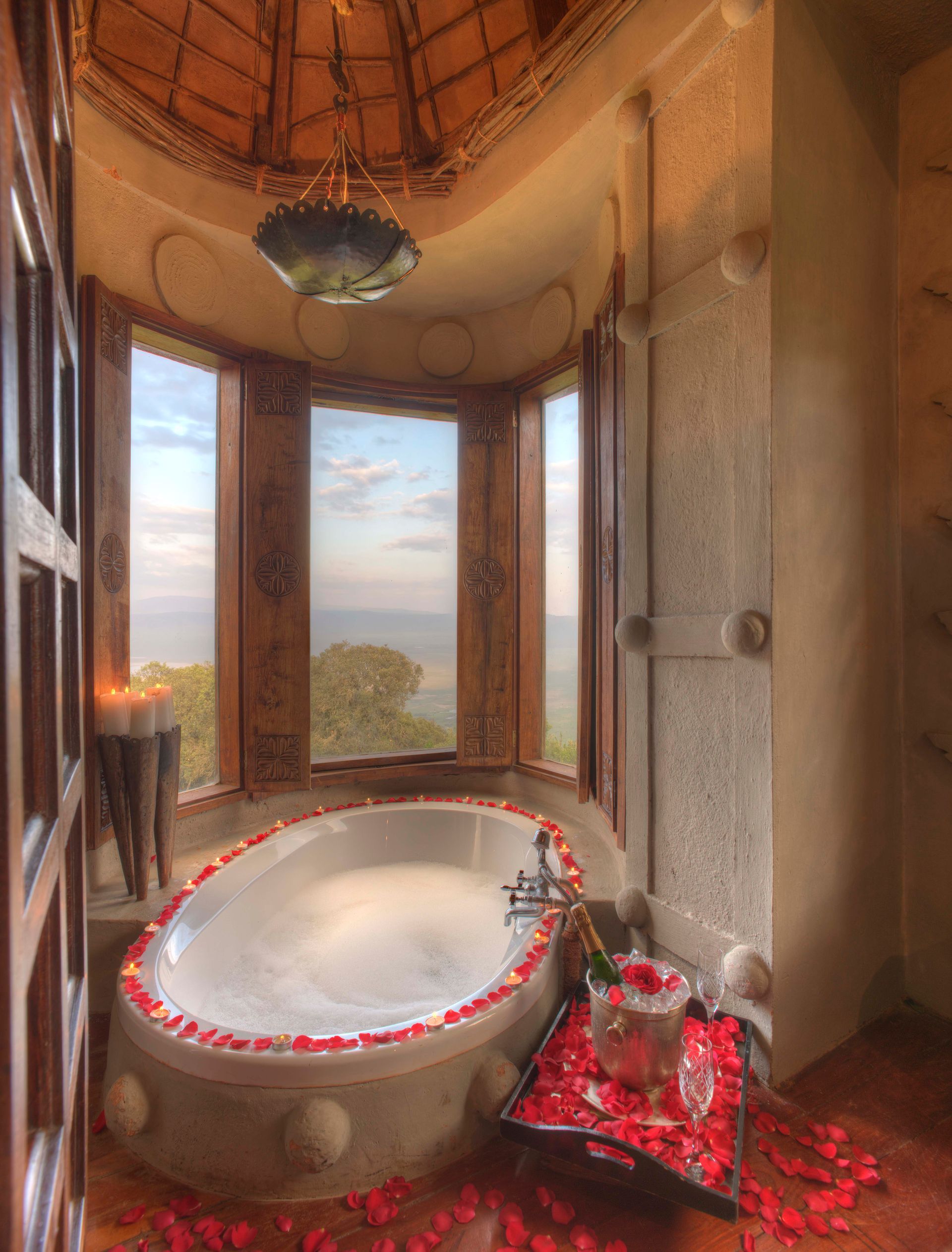 A bathroom with a large bathtub surrounded by rose petals at a lodge in Africa.