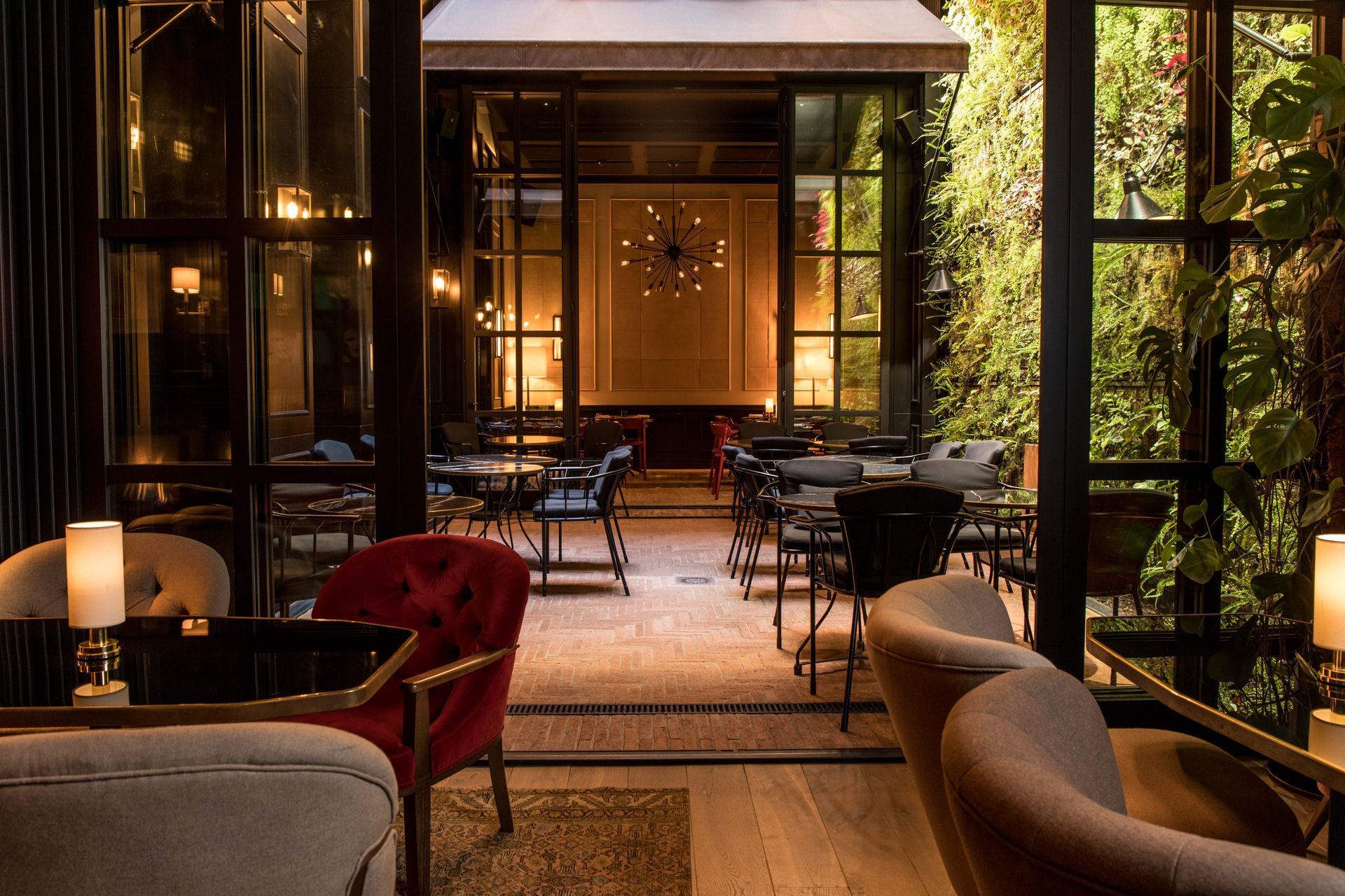 A restaurant with tables , chairs , lamps and a green wall at Wittmore Hotel in Barcelona, Spain.