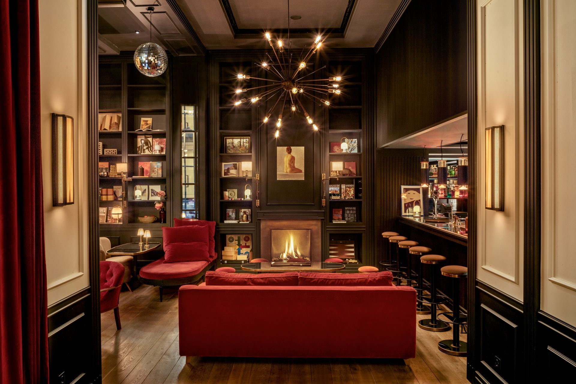 A living room with a red couch and a fireplace at Wittmore Hotel in Barcelona, Spain.