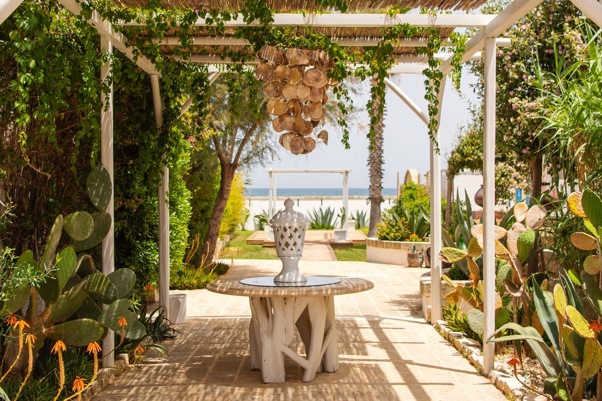 There is a table under a pergola with a vase on it at Canne Bianche Lifestyle Hotel in Puglia, Italy.