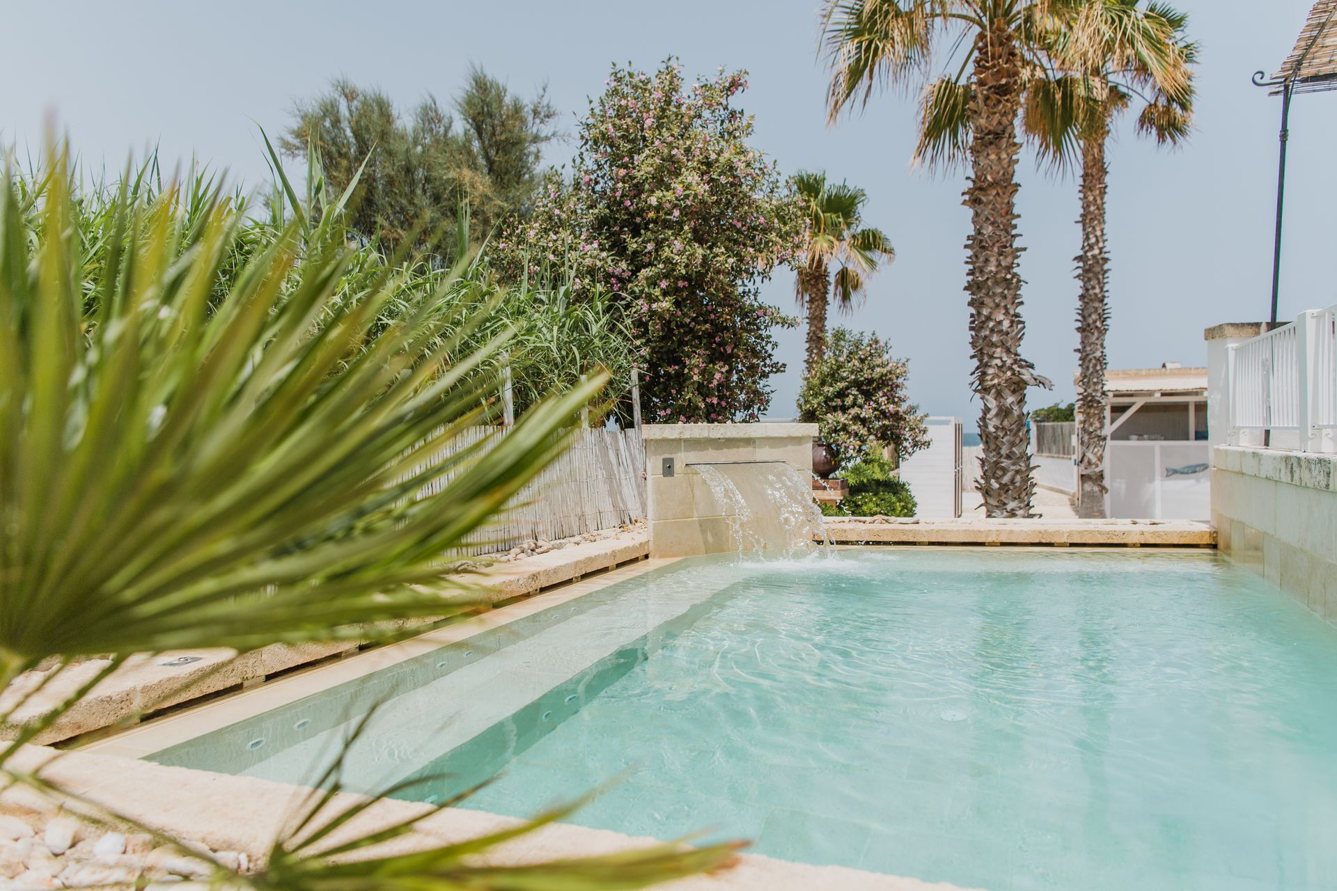 A swimming pool with palm trees in the background at Canne Bianche Lifestyle Hotel in Puglia, Italy.