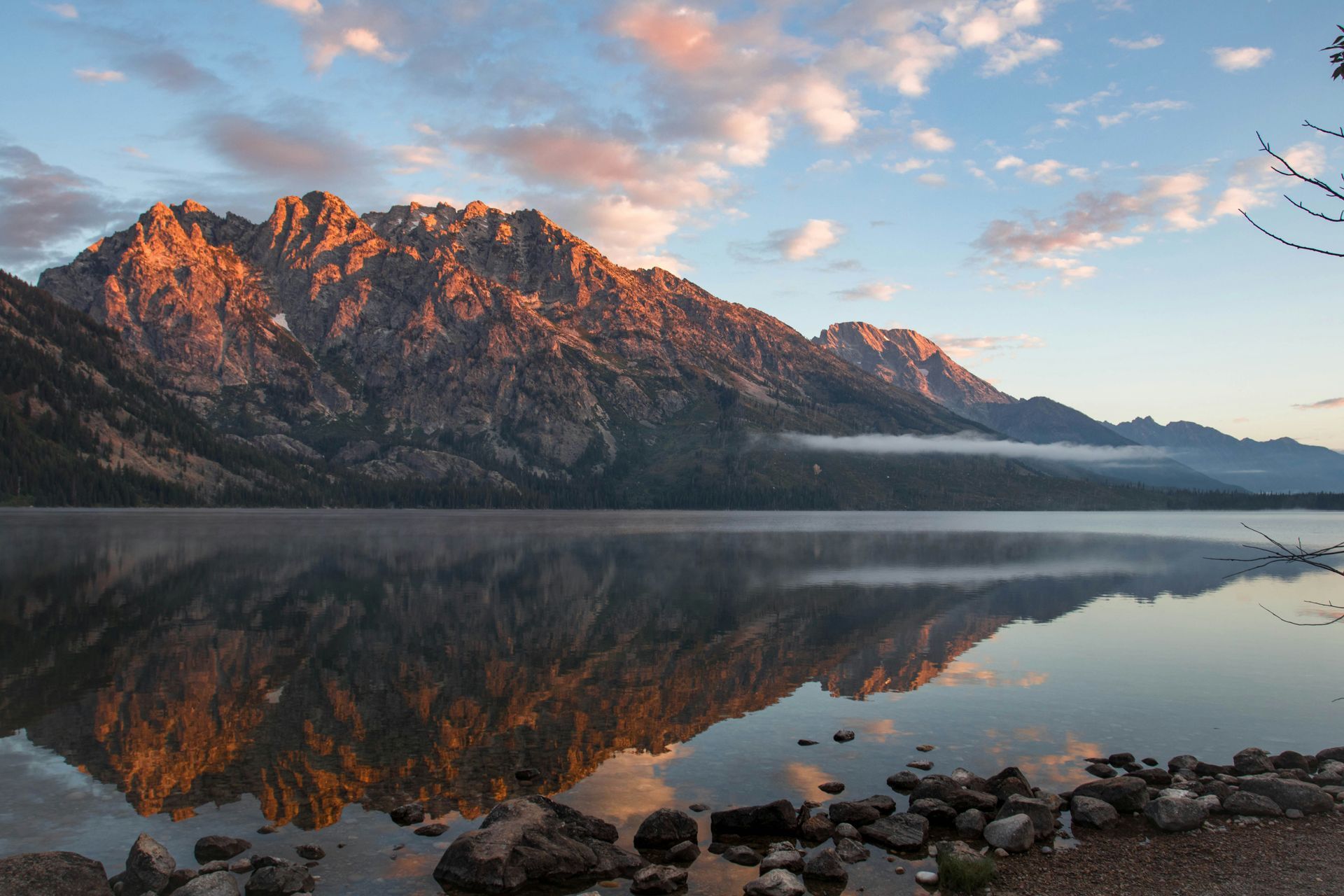 A lake with mountains in the background is reflected in the water.