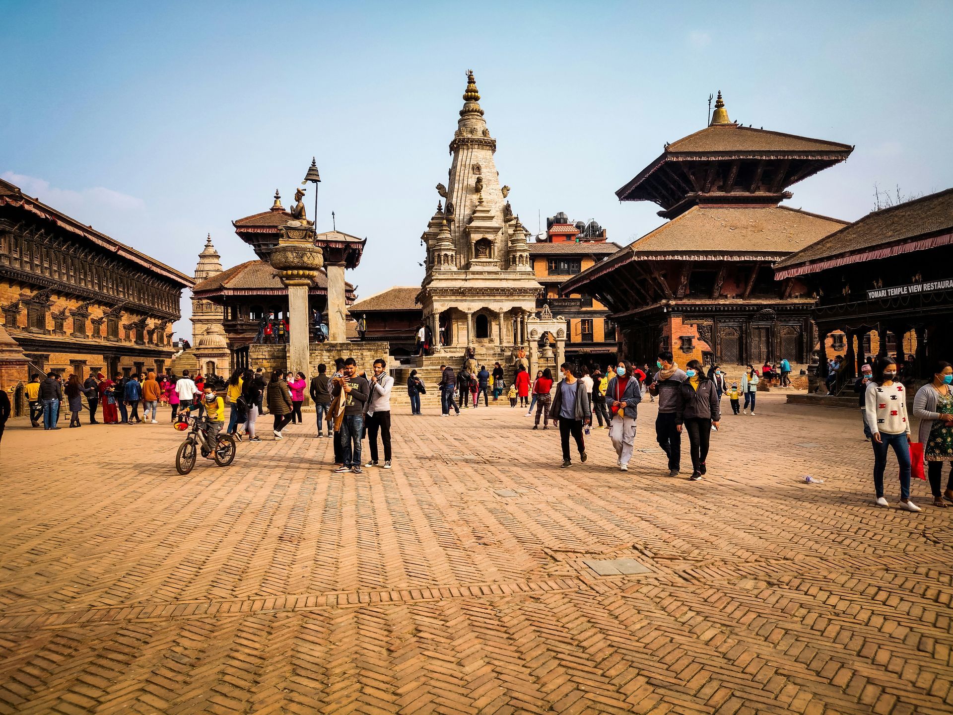 Cobblestone square with Nepalese temples and people walking in Bhaktapur, Nepal.